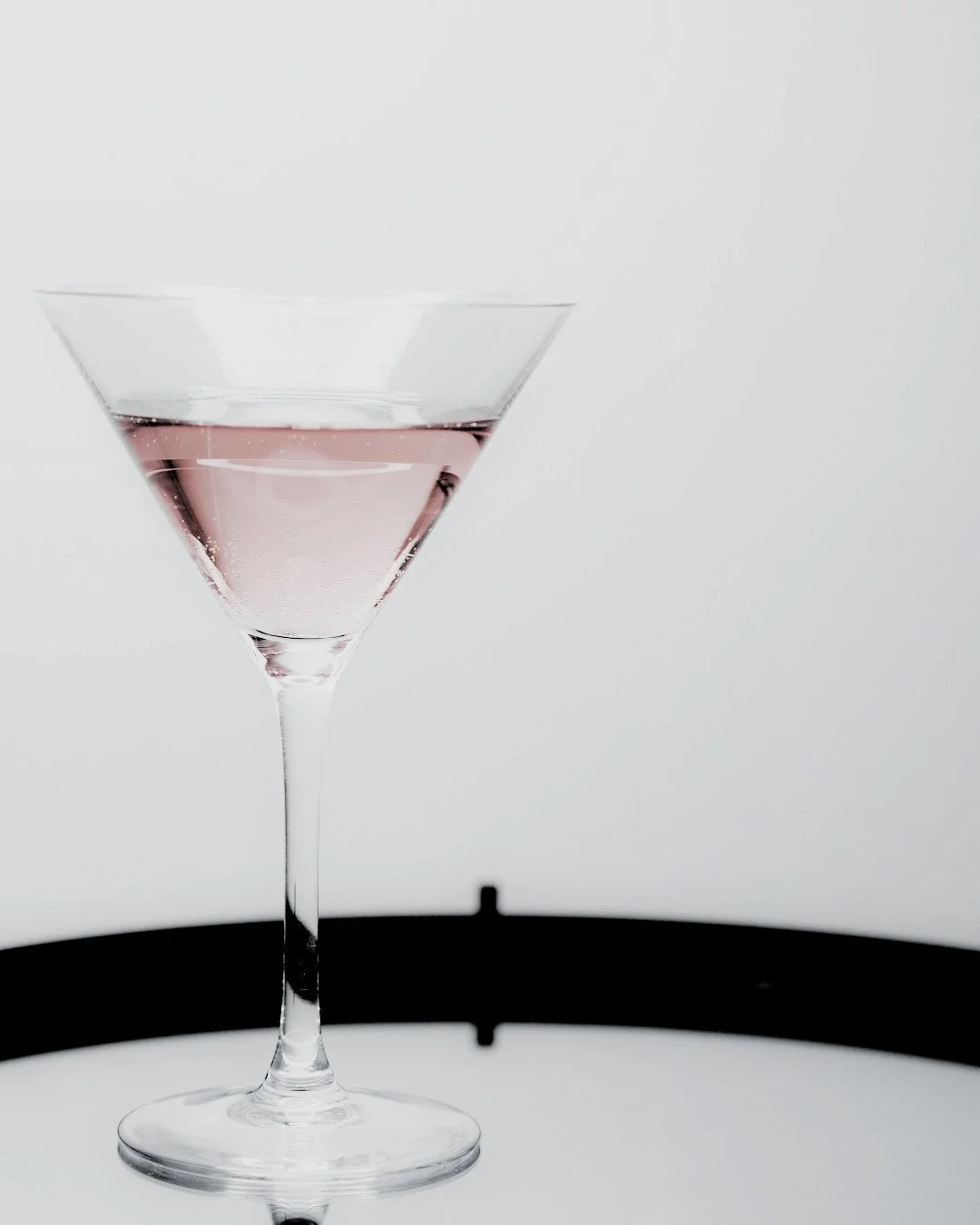 Cocktail glass with pink liquor served on a silver tray, evoking private concierge service and refined personal attention