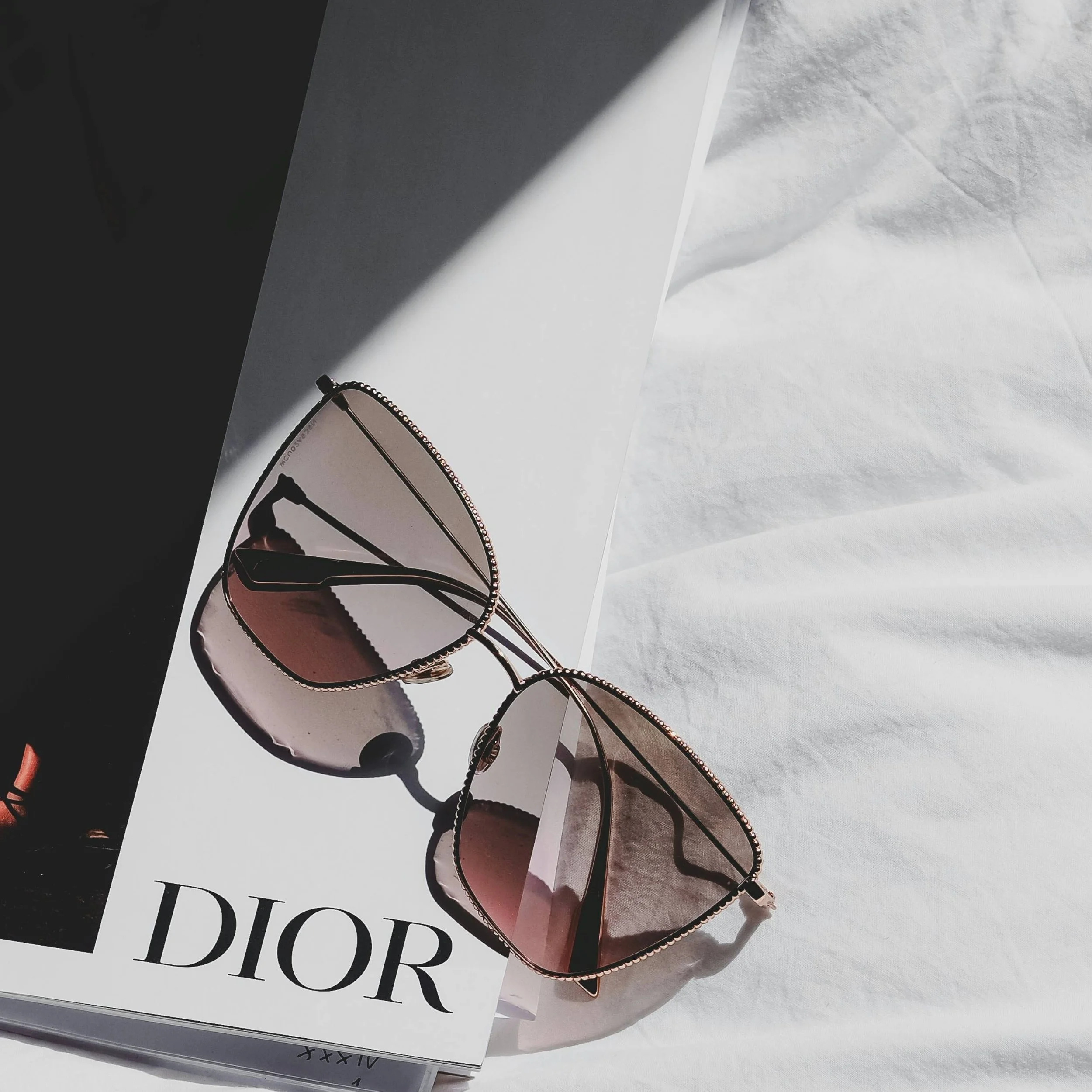 Luxury fashion and lifestyle inspiration – Dior book with elegant sunglasses – link to Pinterest boards