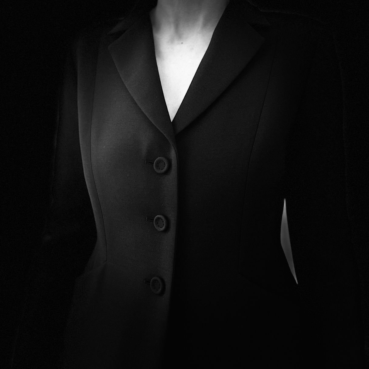 Dark portrait of a woman in an iconic black Dior Bar jacket, showcasing timeless luxury fashion style