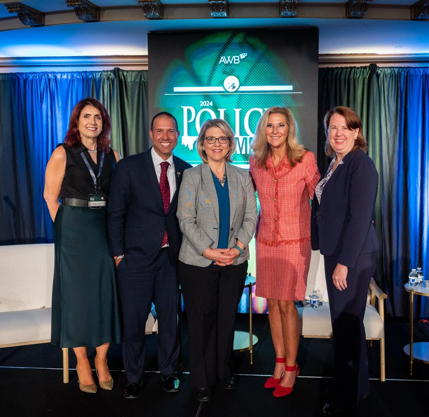 Five individuals standing together at a police conference, posing for a group photo in front of a large screen displaying the words '2024 Police' and a map of the United States.