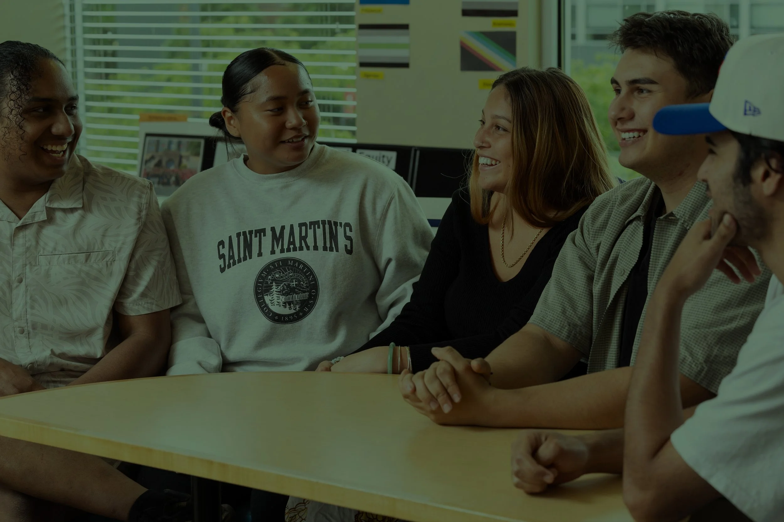 Five young people sitting around a table talking