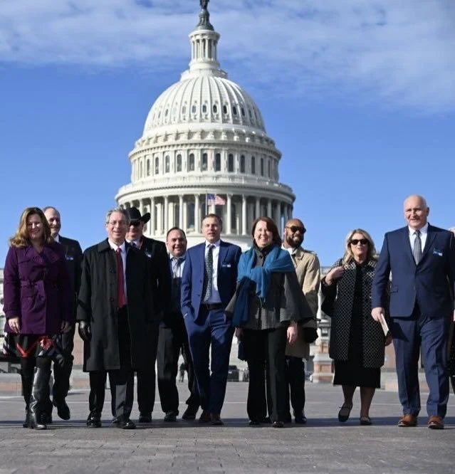 Group of people walking in front of the U.S. Capitol building, with clear blue sky overhead.