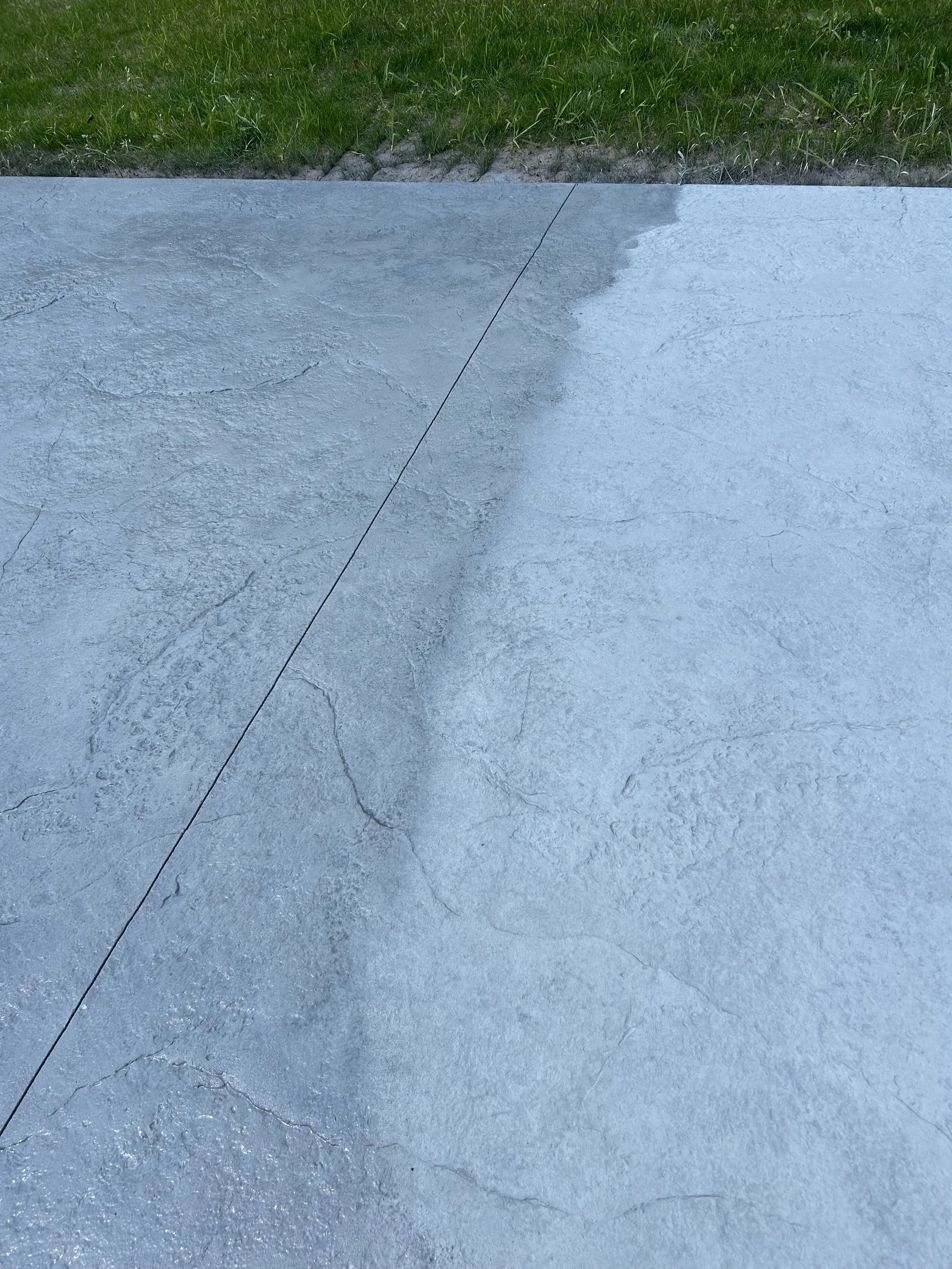 Concrete sidewalk with visible cracks, grass border at the top