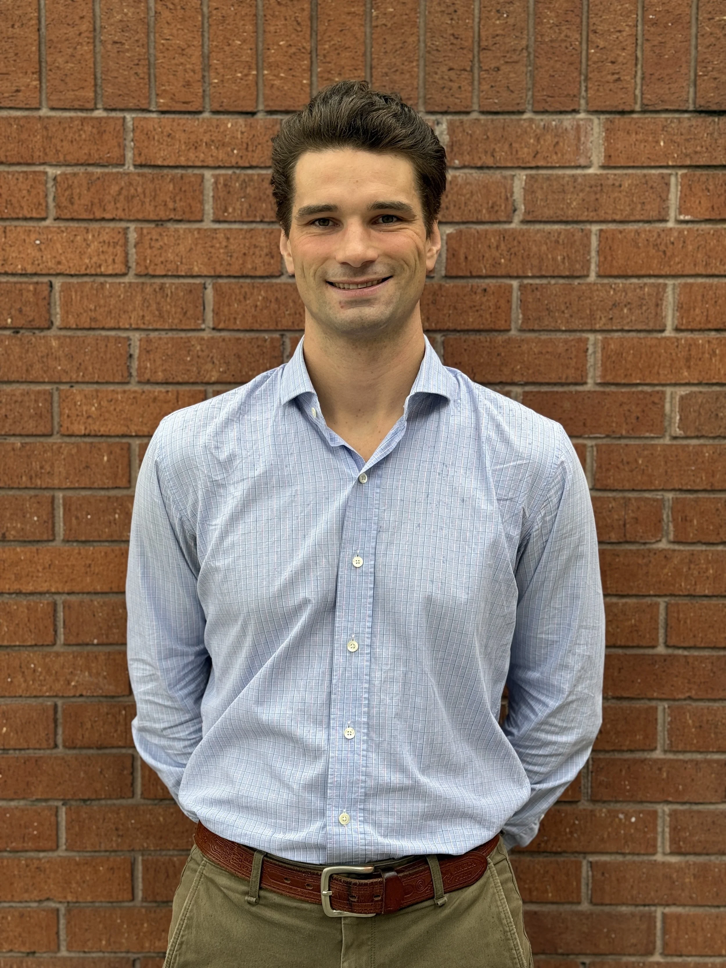 An image of Jakob Walter, standing outdoors in front of a building with stairs, smiling at the camera.