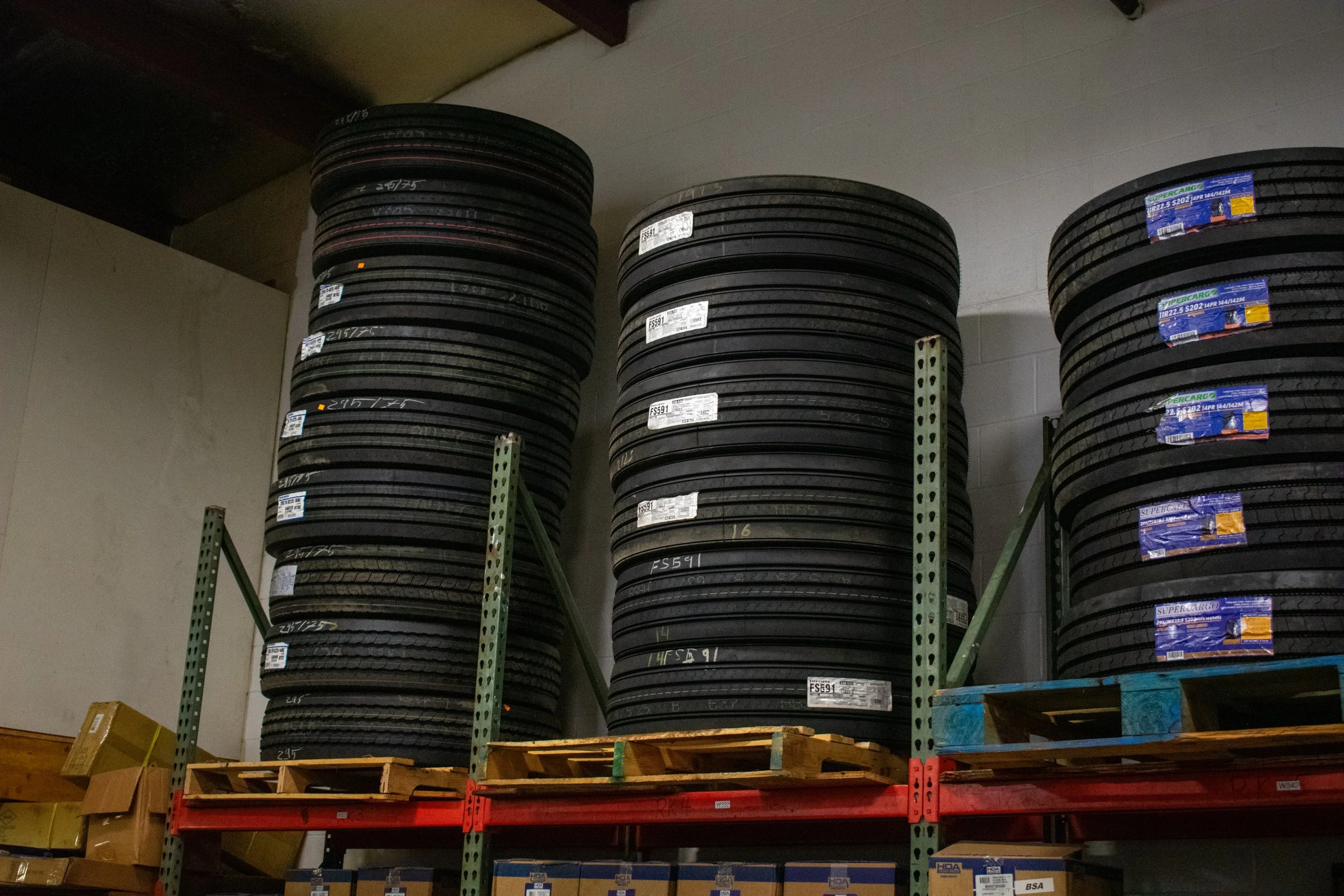 Stacks of black tires stored on metal shelves in a warehouse.