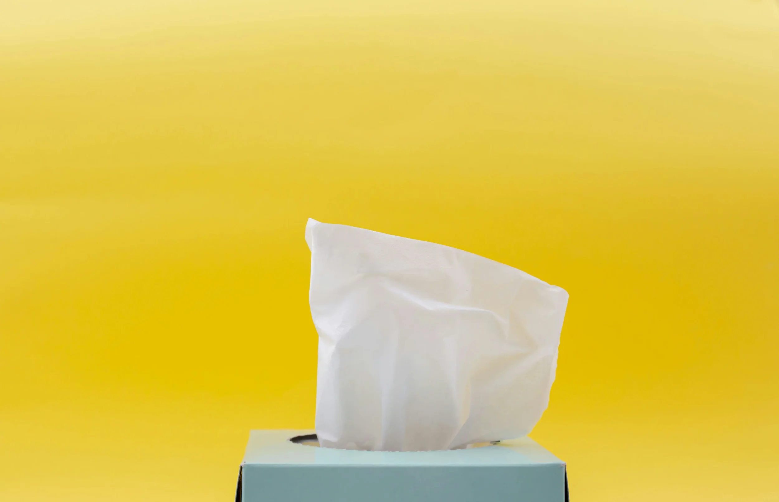 A box of tissues against a yellow background