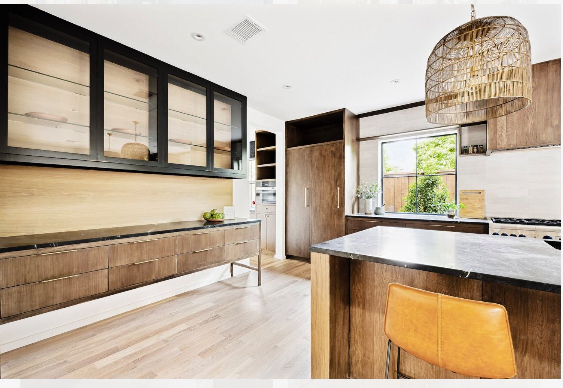 Modern kitchen with wooden cabinets, a black countertop, a large window, and a wicker pendant light.