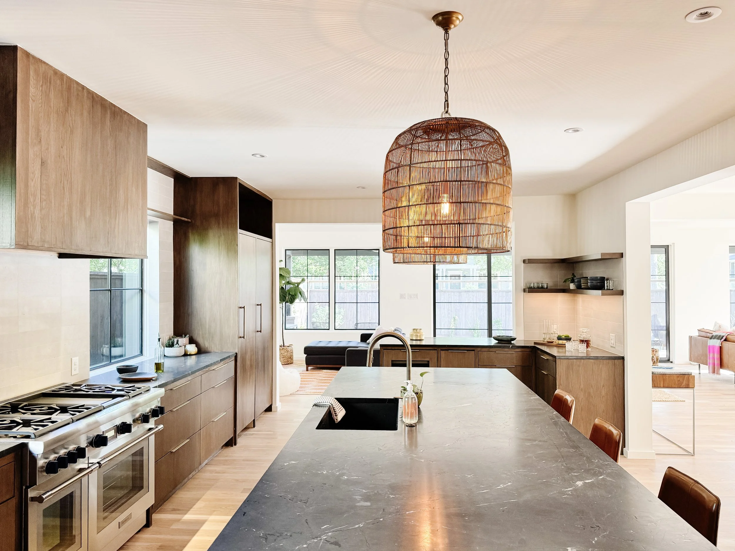 Modern kitchen with wooden cabinets, gray marble island, and a large woven pendant light