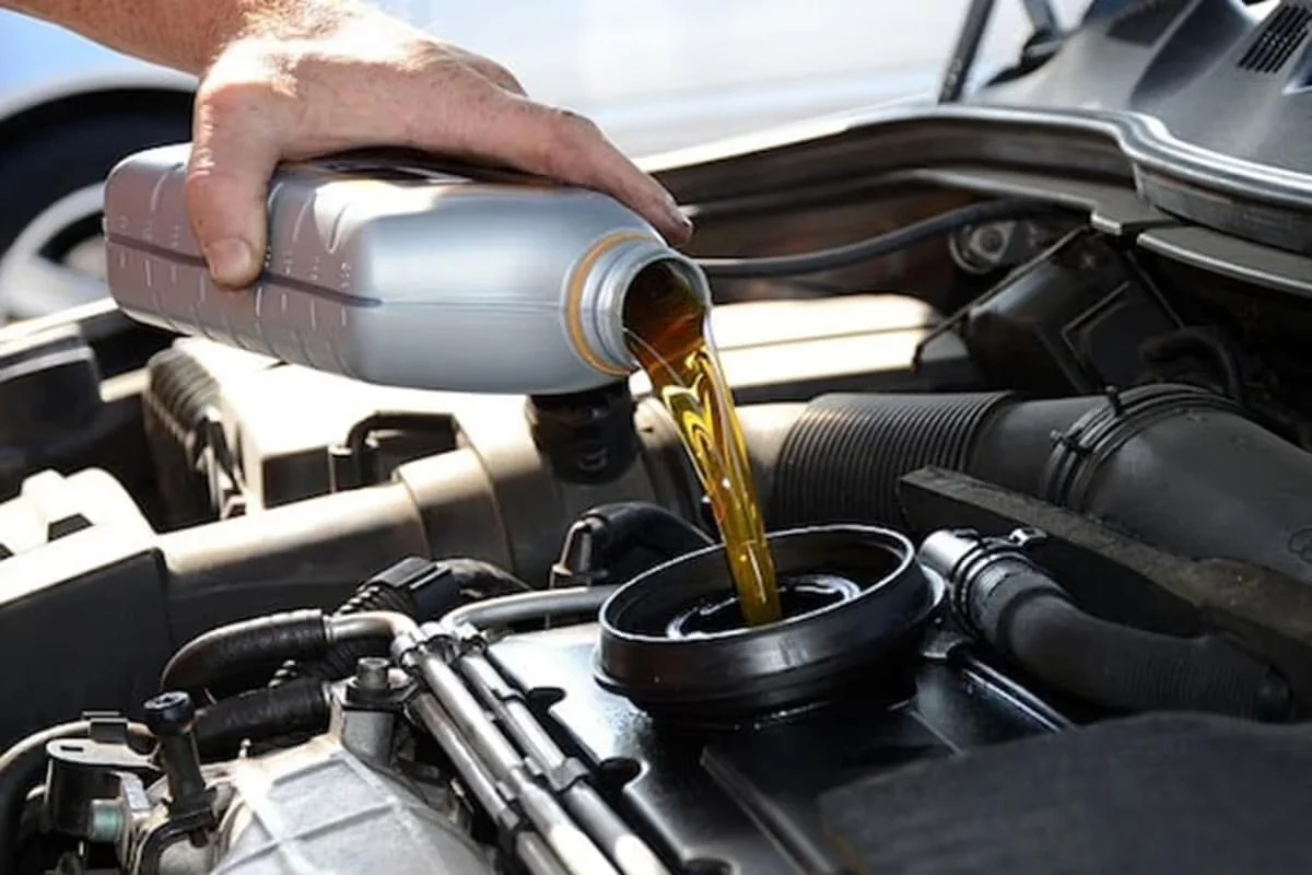 A person pouring synthetic oil into a car engine. (full synthetic, synthetic blend)