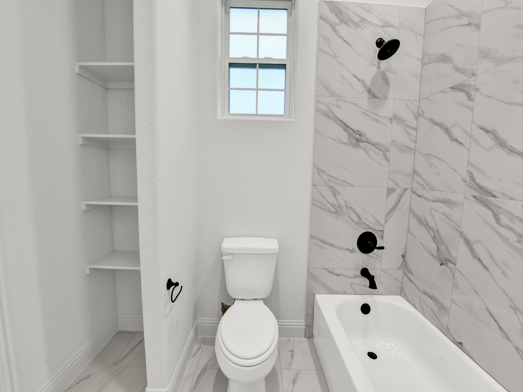 Bathroom with a toilet, bathtub, black fixtures, four tiled shelves, and a small window with frosted glass.