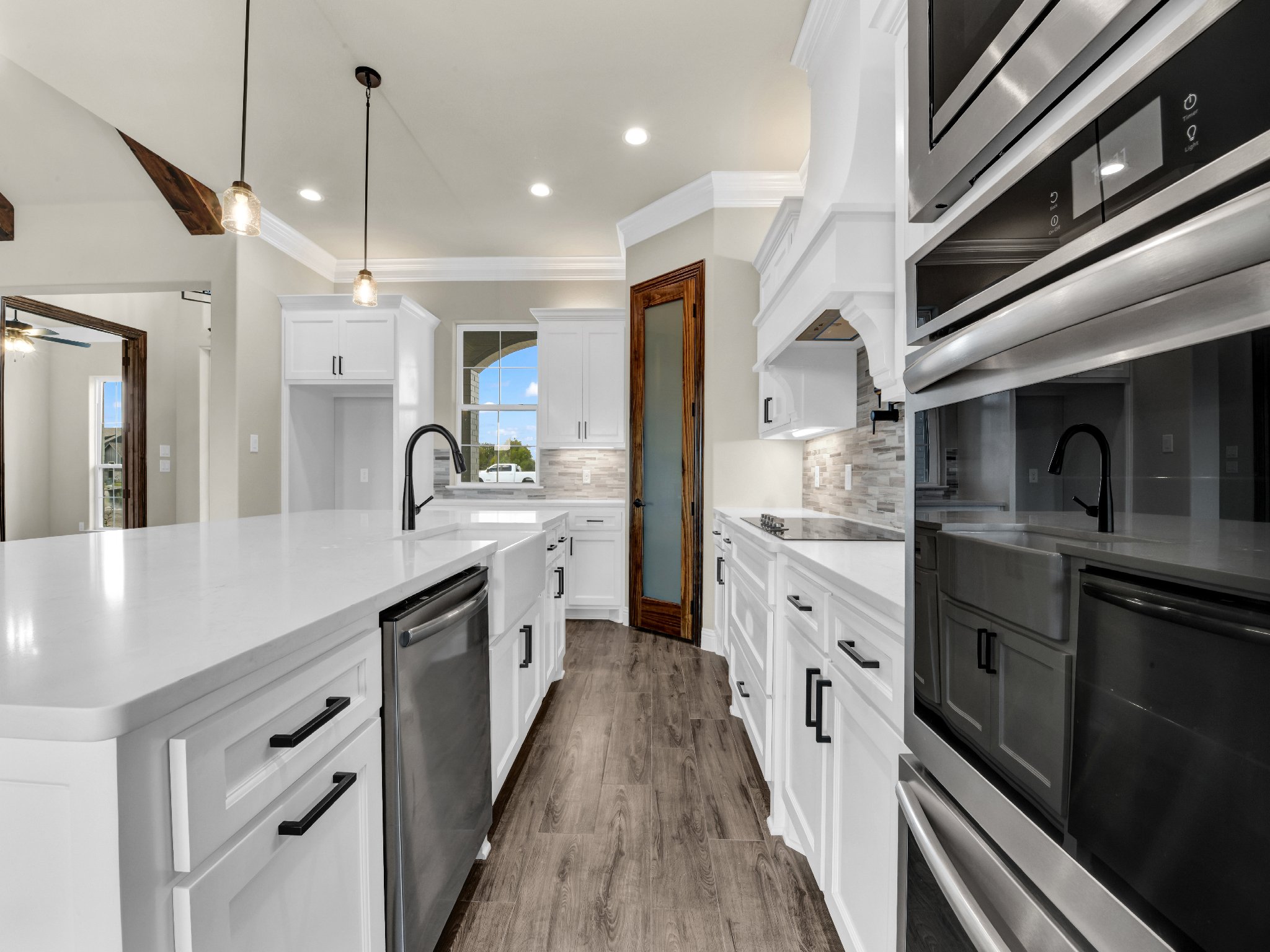 Modern kitchen with white cabinets, black hardware, stainless steel appliances, and wood flooring