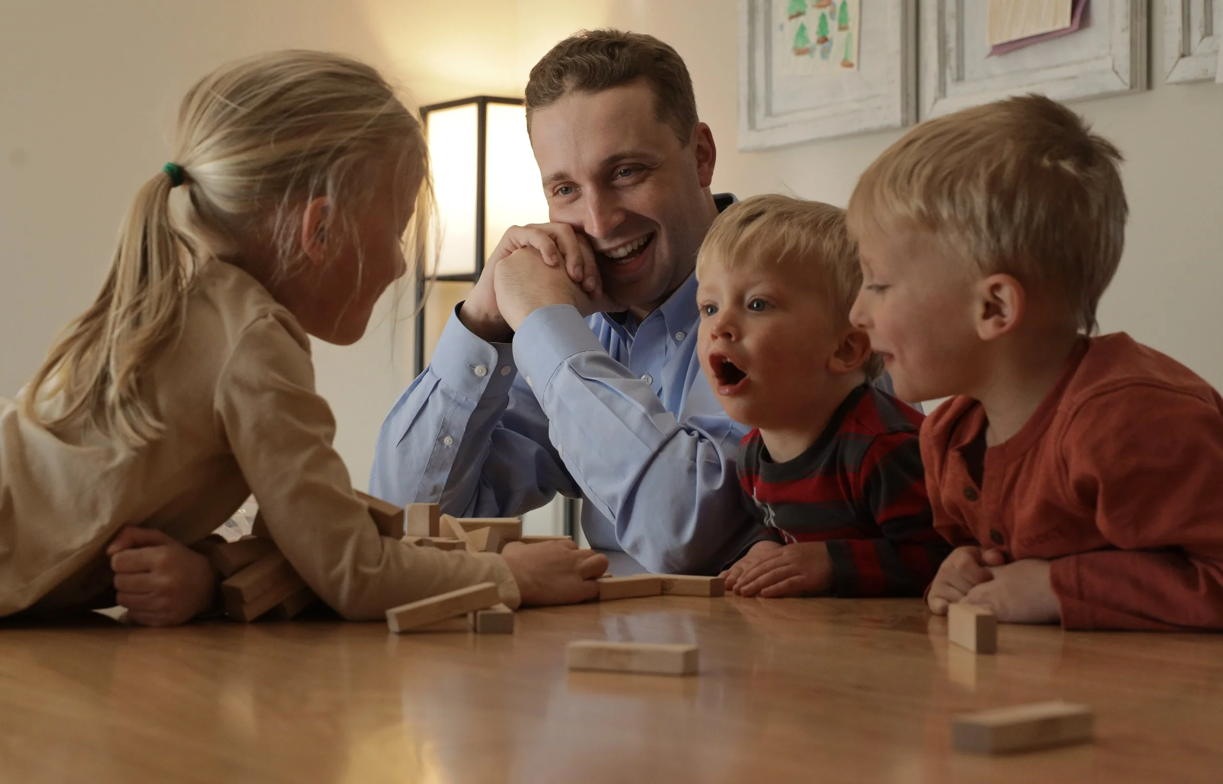 From left: Miriam, 5, knocks over the tower during a game of Jenga as Harrison, Richard, 2, and Lewis, 4, laugh on March 20, 2025, at their home in Fulton, Mo. “They are wonderful,” Harrison said. “There’s nothing more rewarding after all the work we