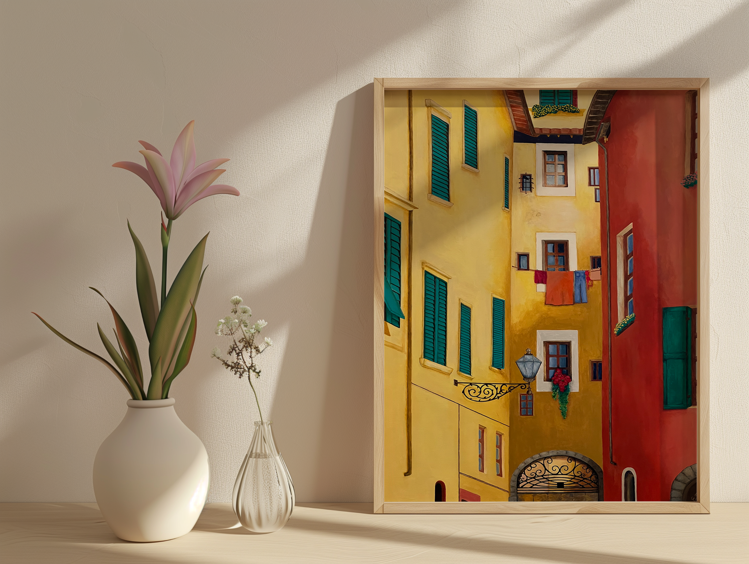 A framed painting of colorful European-style buildings with shutters and laundry hanging, placed on a light-colored surface.