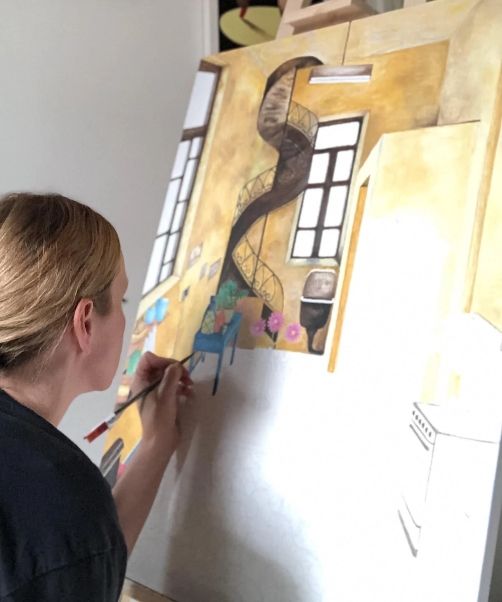 An artist painting a colorful interior scene of a room with a spiral staircase, large windows, and a chair with flowers on it.