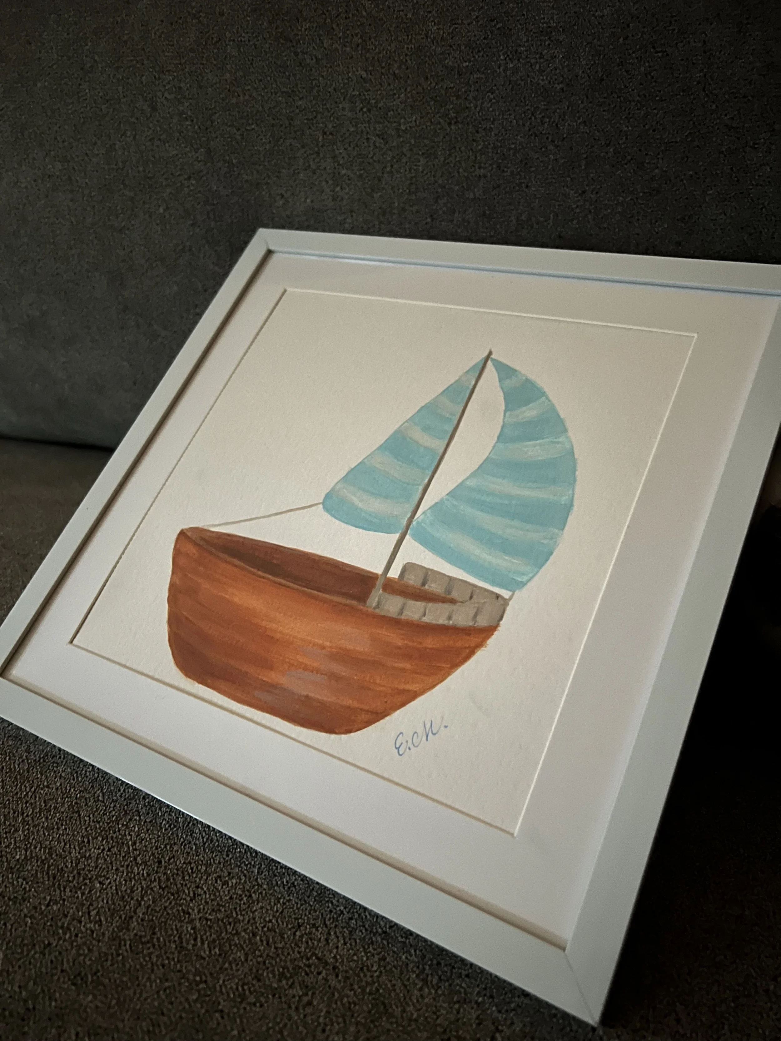 Watercolor painting of a small brown sailboat with striped blue sails, signed E.M.
