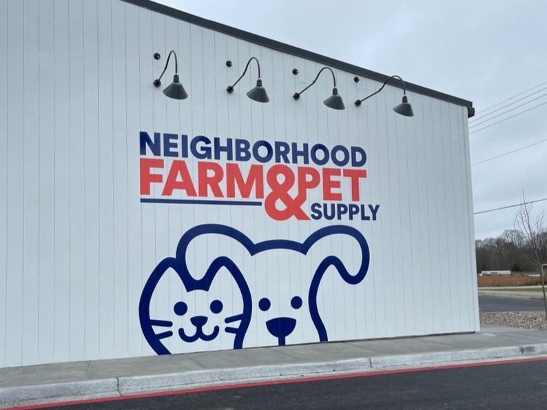 Exterior wall of a store named Neighborhood Farm & Pet Supply with a graphic of a cat and dog in blue and red text.