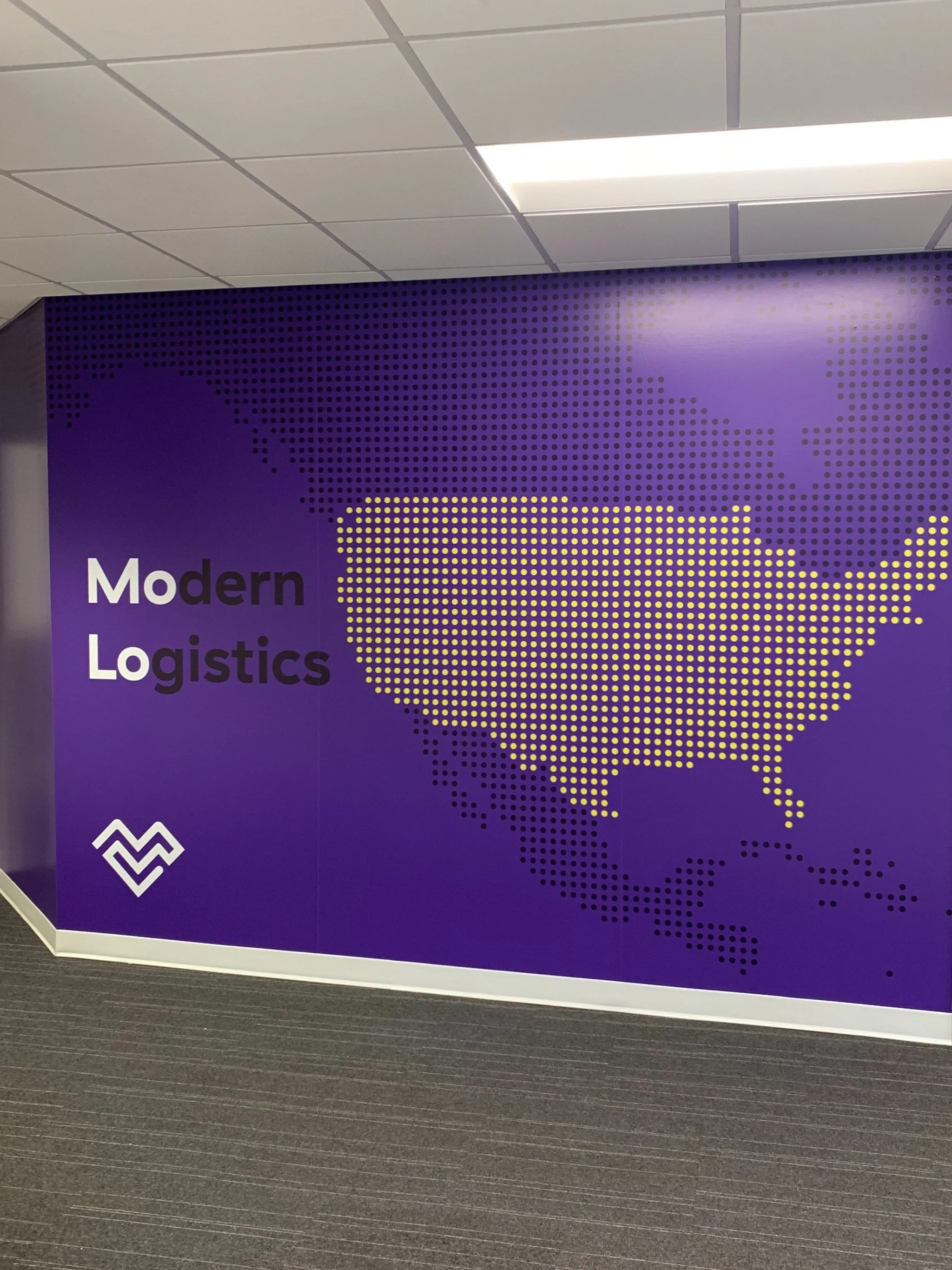 Purple wall with a dotted map of the United States displaying the phrase 'Modern Logistics' and a white logo.