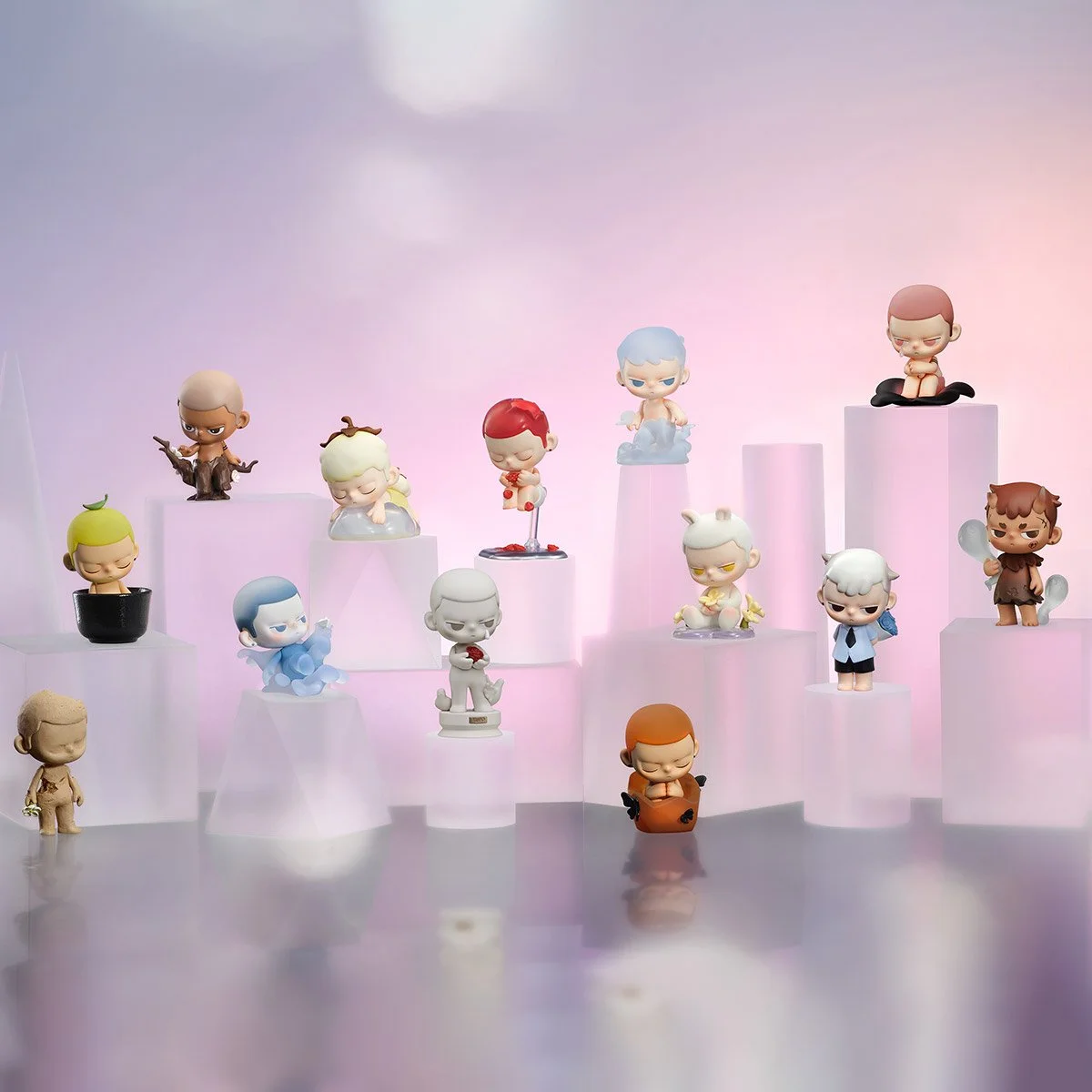 Group image of multiple KUBO figures arranged on illuminated white pedestal blocks against a soft pink-to-purple background, including characters seated in clouds, a black bowl, and a central red-haired figure on a clear stand holding a heart.