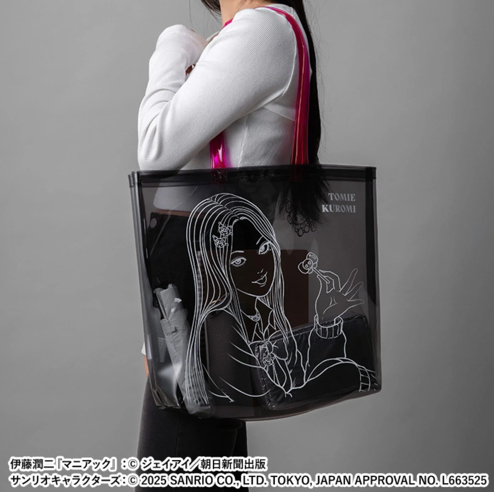 Person holding a translucent black tote bag printed with Tomie line art and Kuromi-themed design elements.