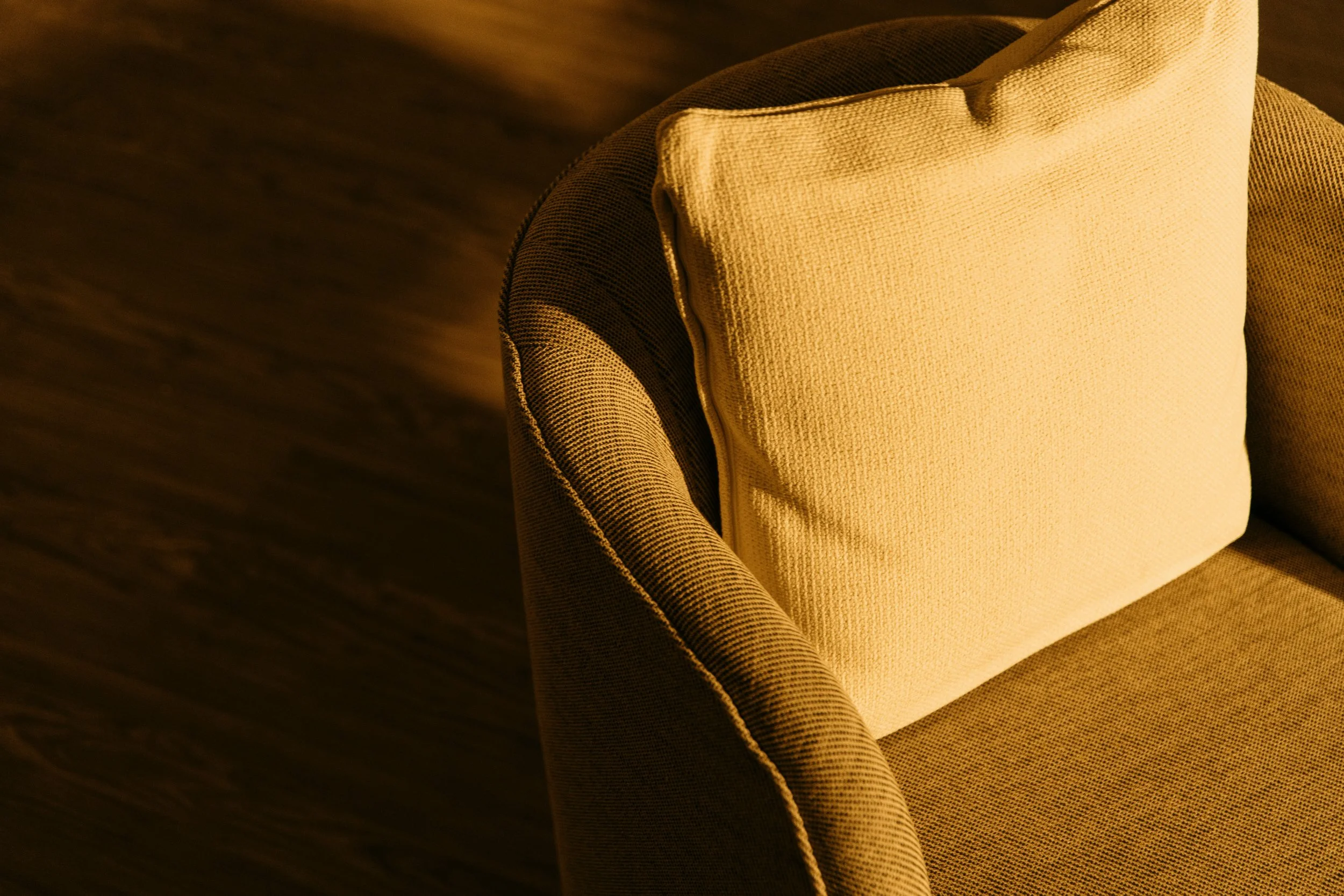 A warm, inviting therapy chair in soft light — evoking comfort, safety, and space for reflection.