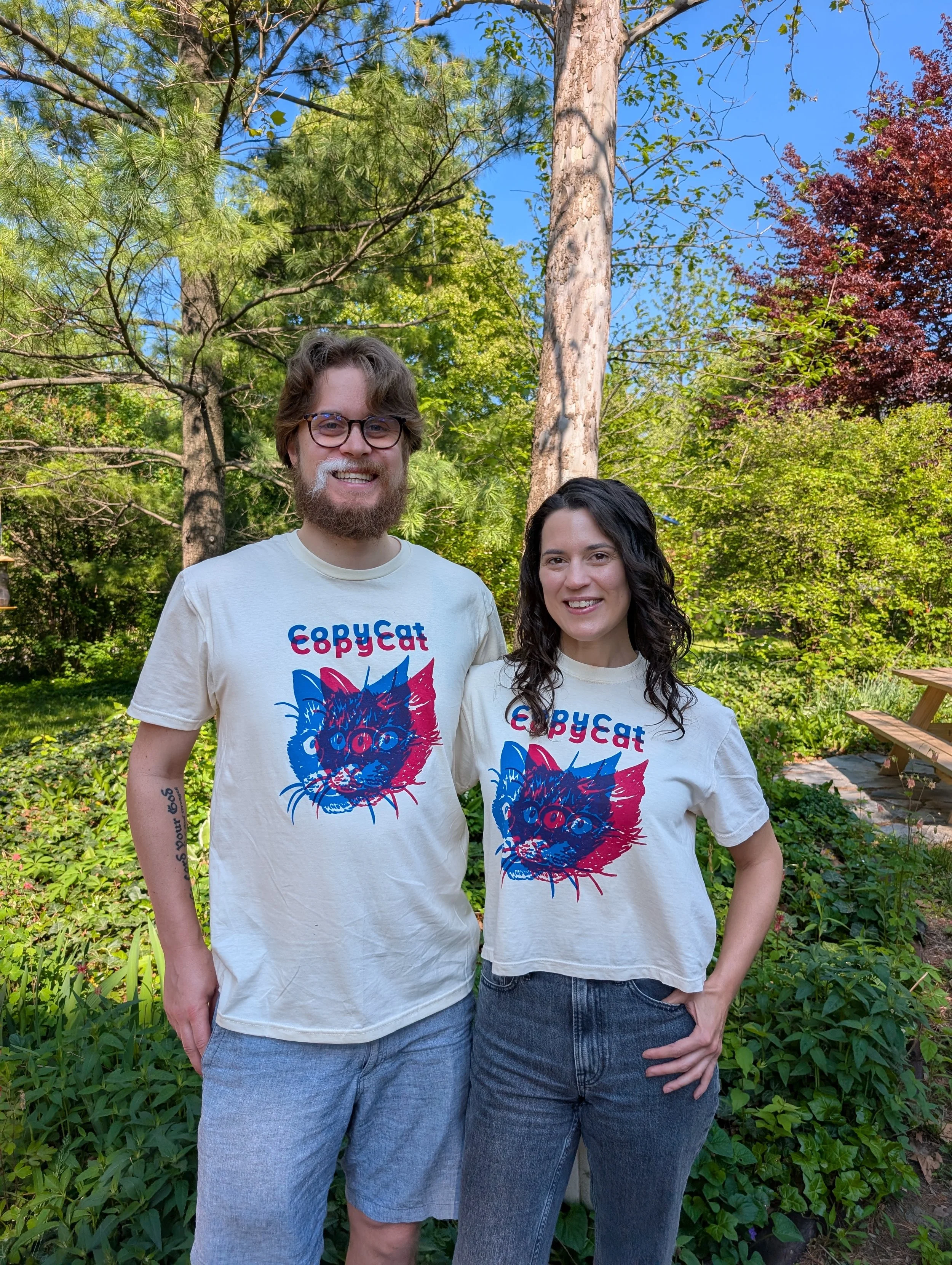 Two people wearing CopyCat t-shirts, which features illustrated cat heads printed in pink and blue.