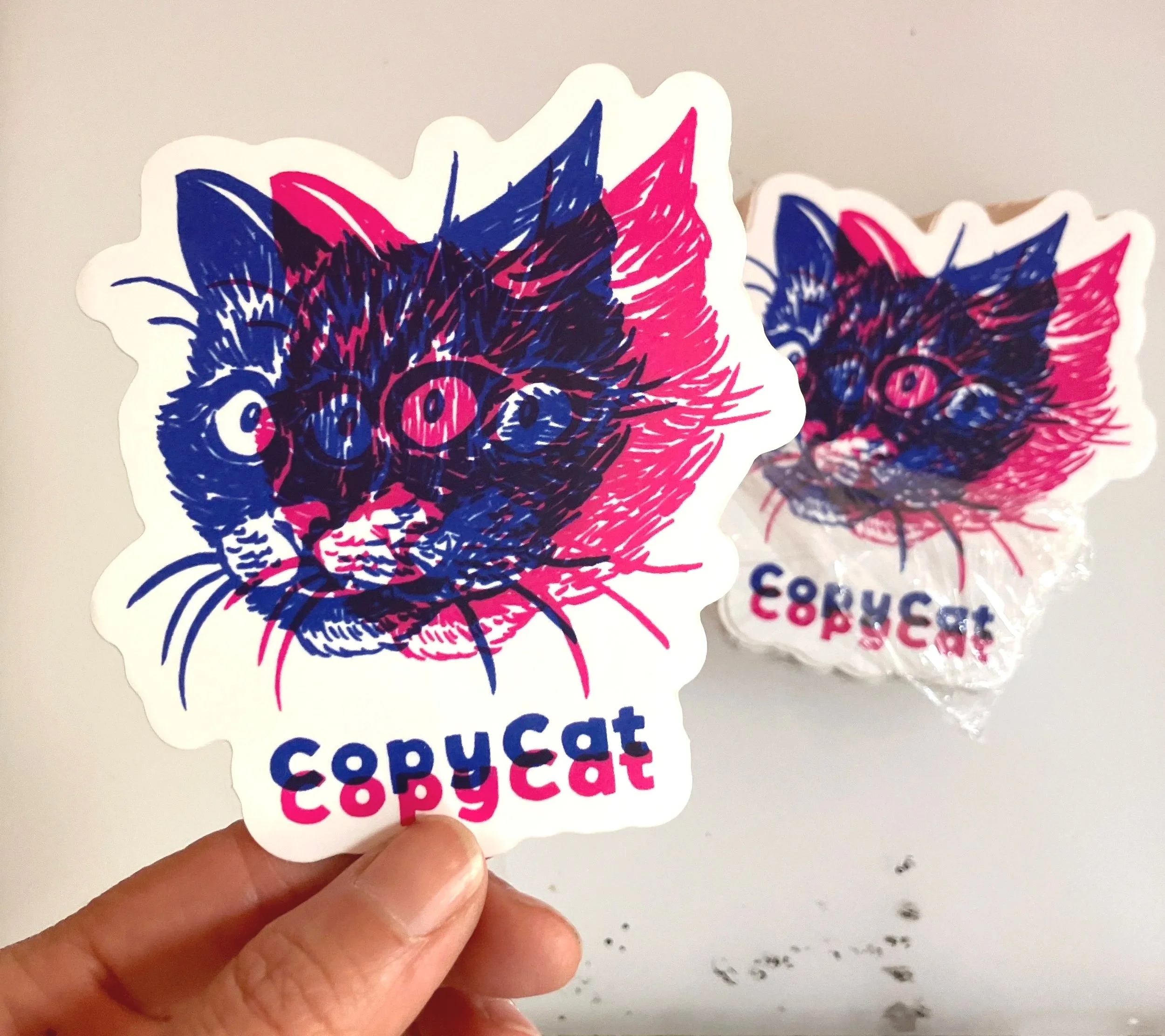 CopyCat sticker with overlaid cat heads in pink and blue