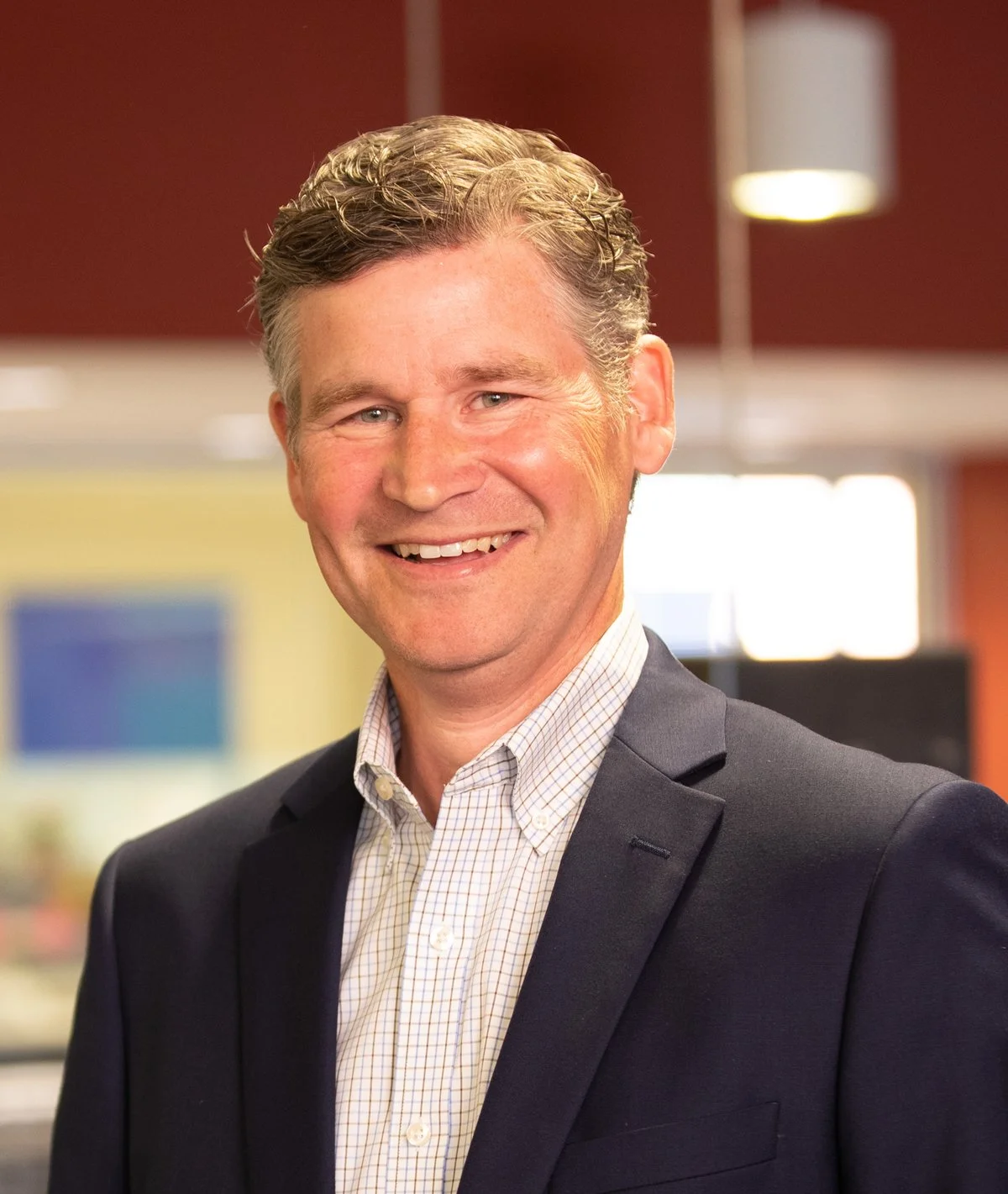 A smiling man in a business suit in an office environment.