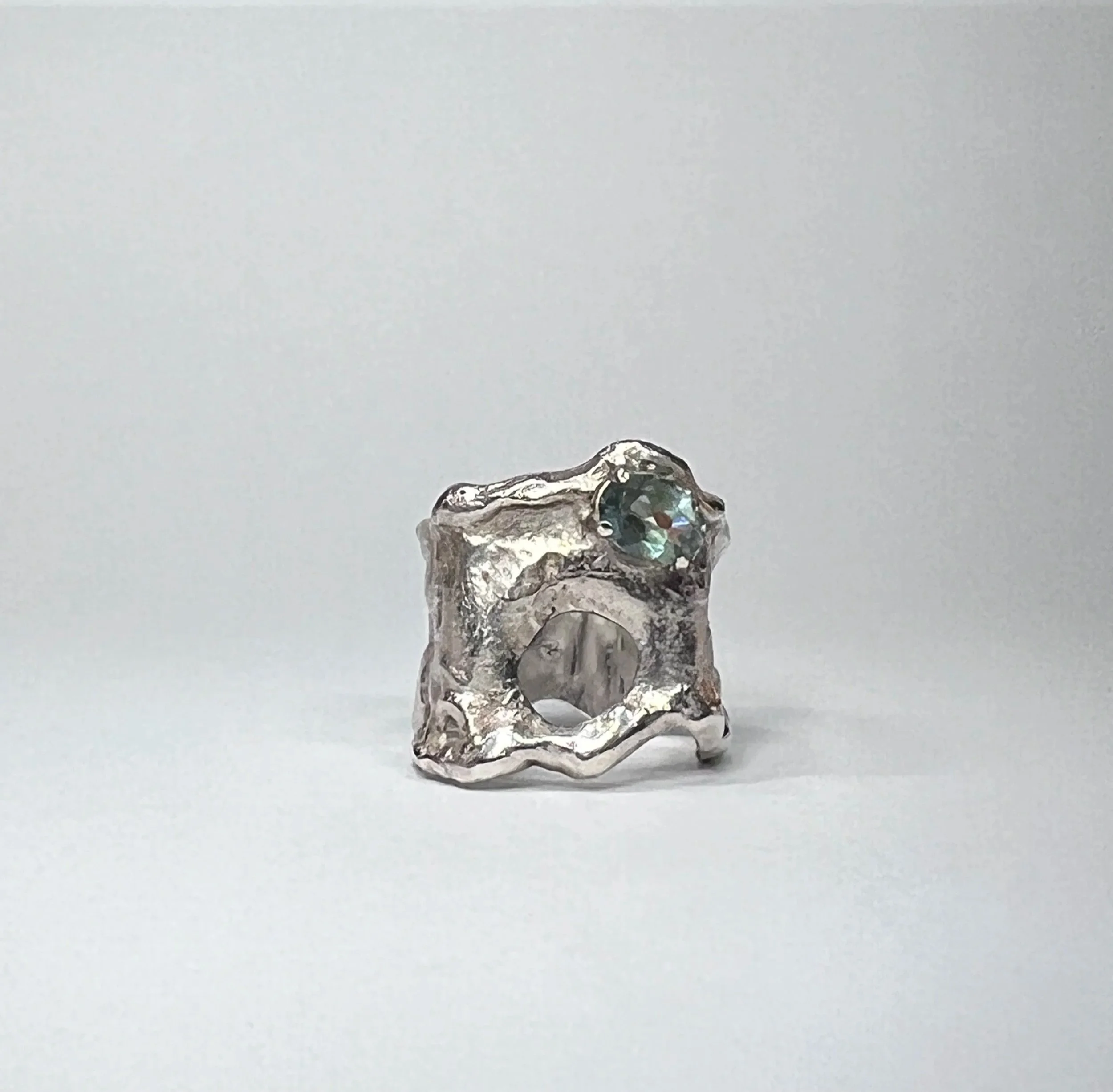 A small, crumpled piece of aluminum foil with an iridescent, shiny surface, placed on a plain white background.