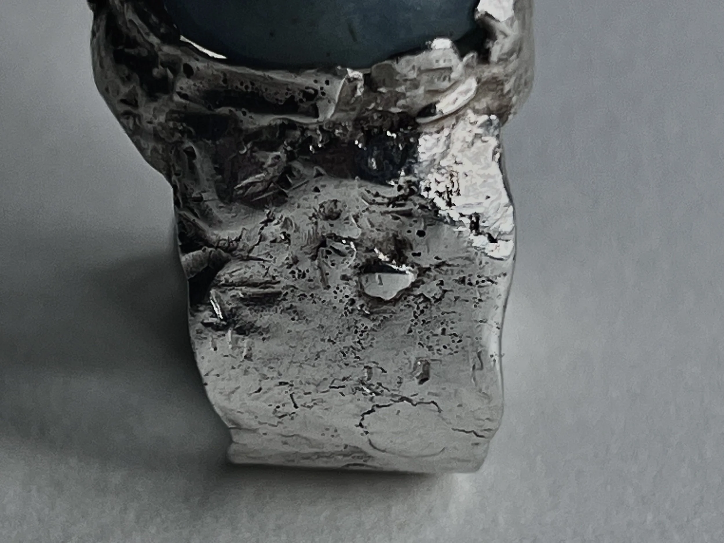 A crumpled silver foil wrapper with black, white, and brown splashes on a light gray surface.