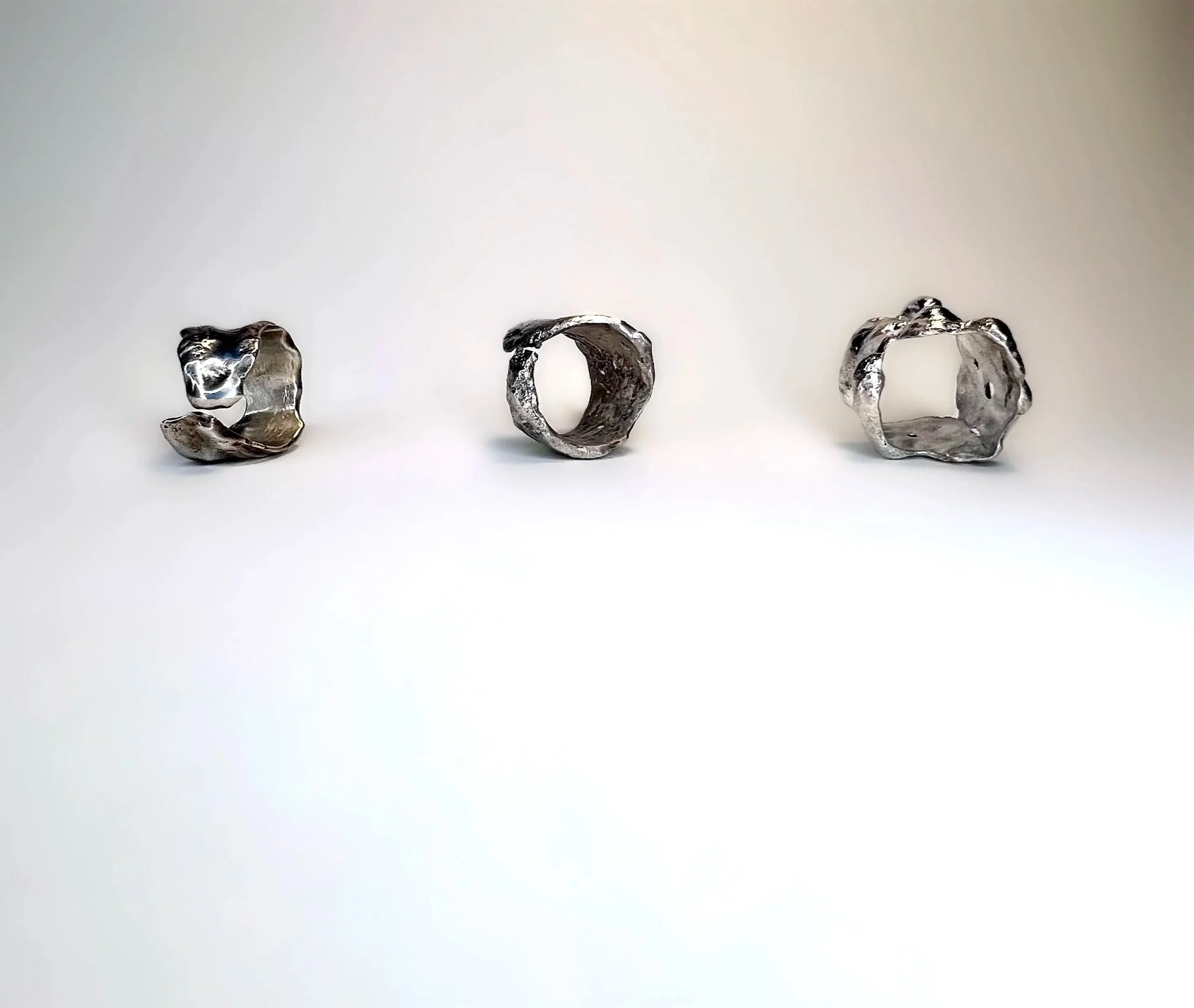 Three irregularly shaped metallic rings placed on a plain white surface with a plain white background.