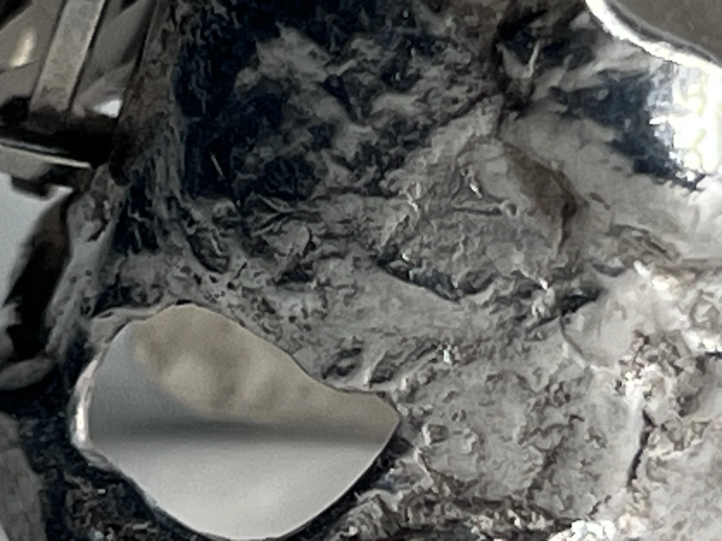 Close-up of a washing machine drum with black and white shredded material inside.