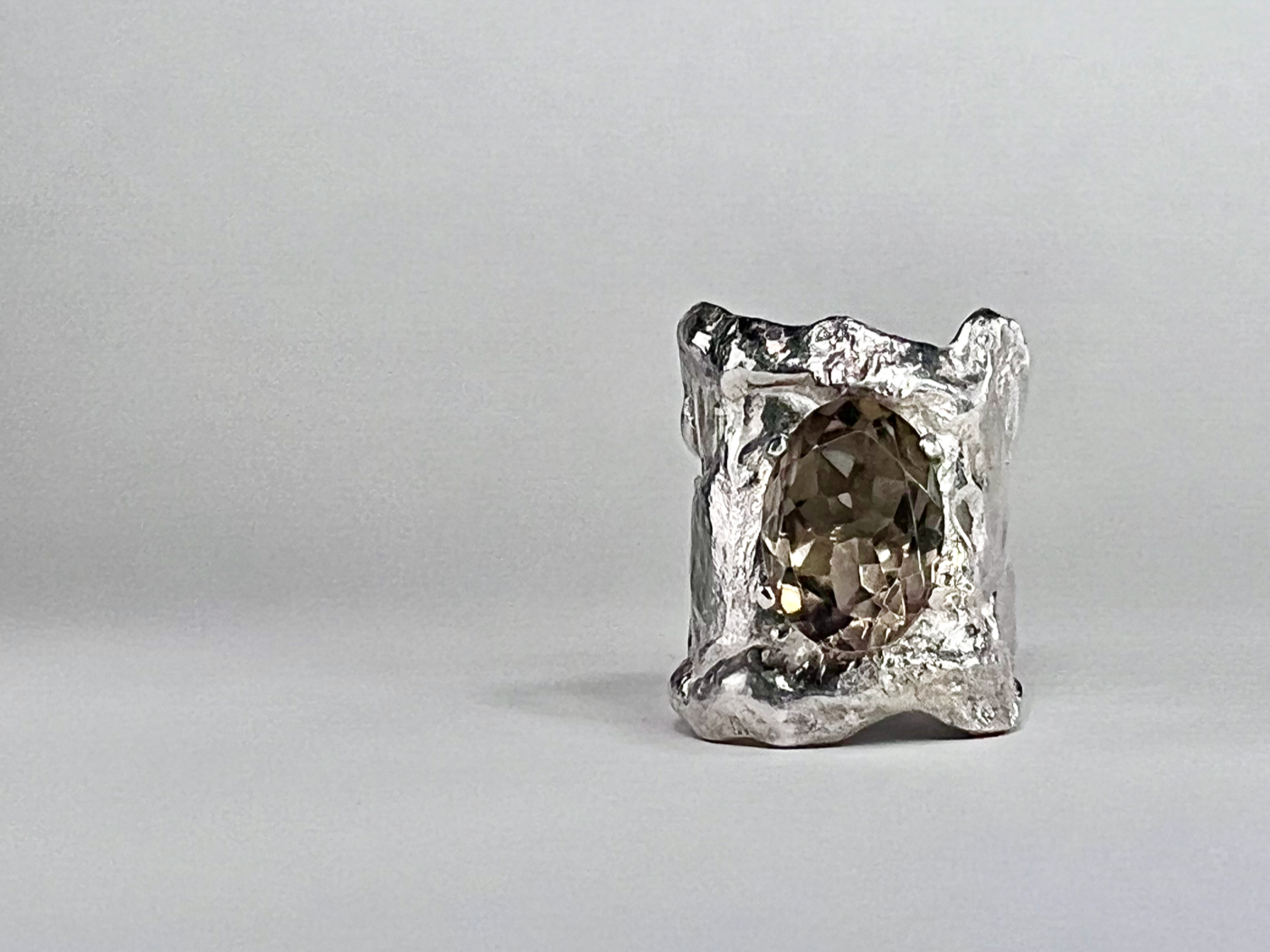 A silver ring with a large oval-cut gemstone set in a textured band against a plain white background.