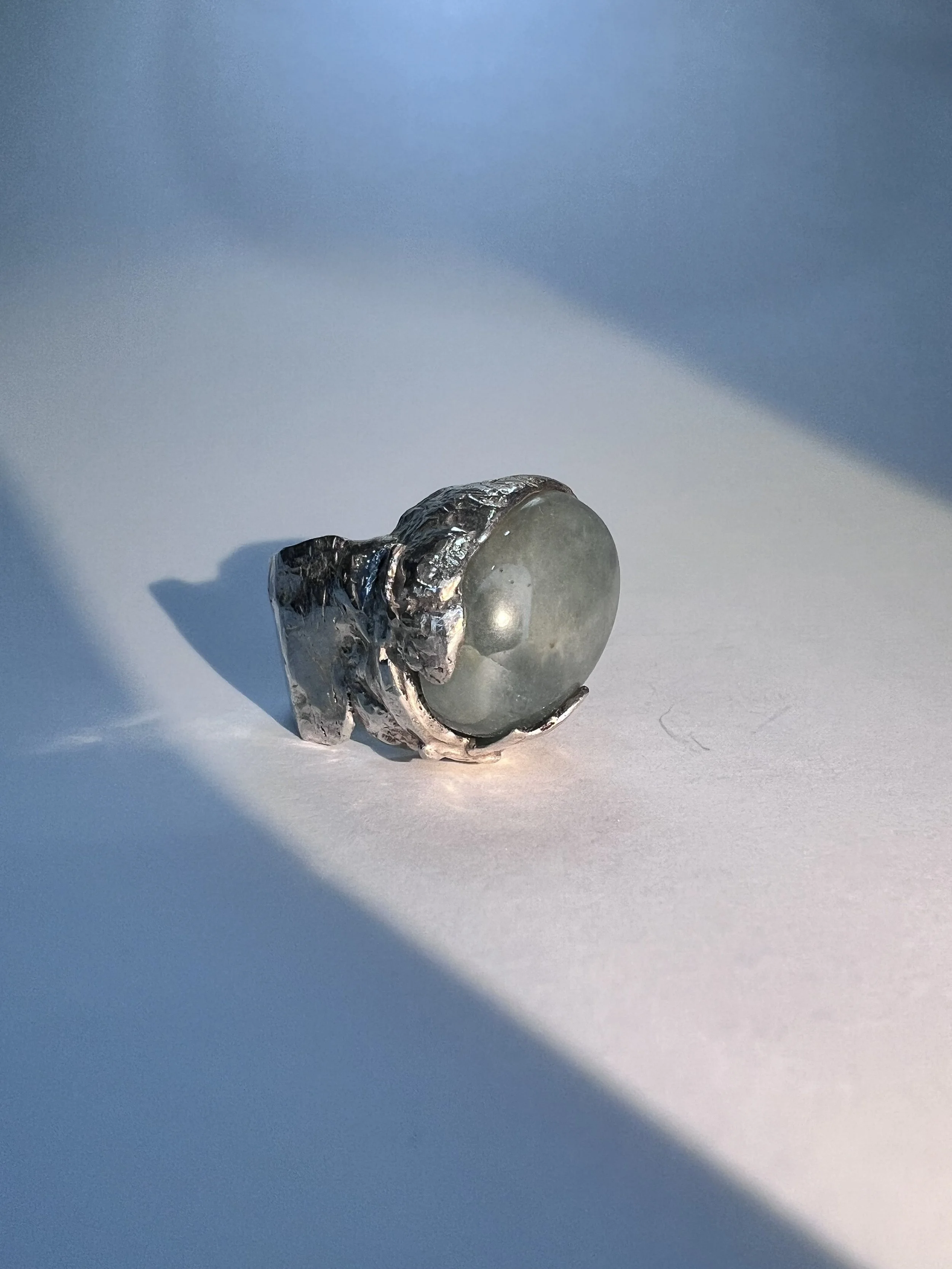A round lightbulb with a metal screw base, wrapped in aluminum foil, placed on a white surface with a gradient blue background.