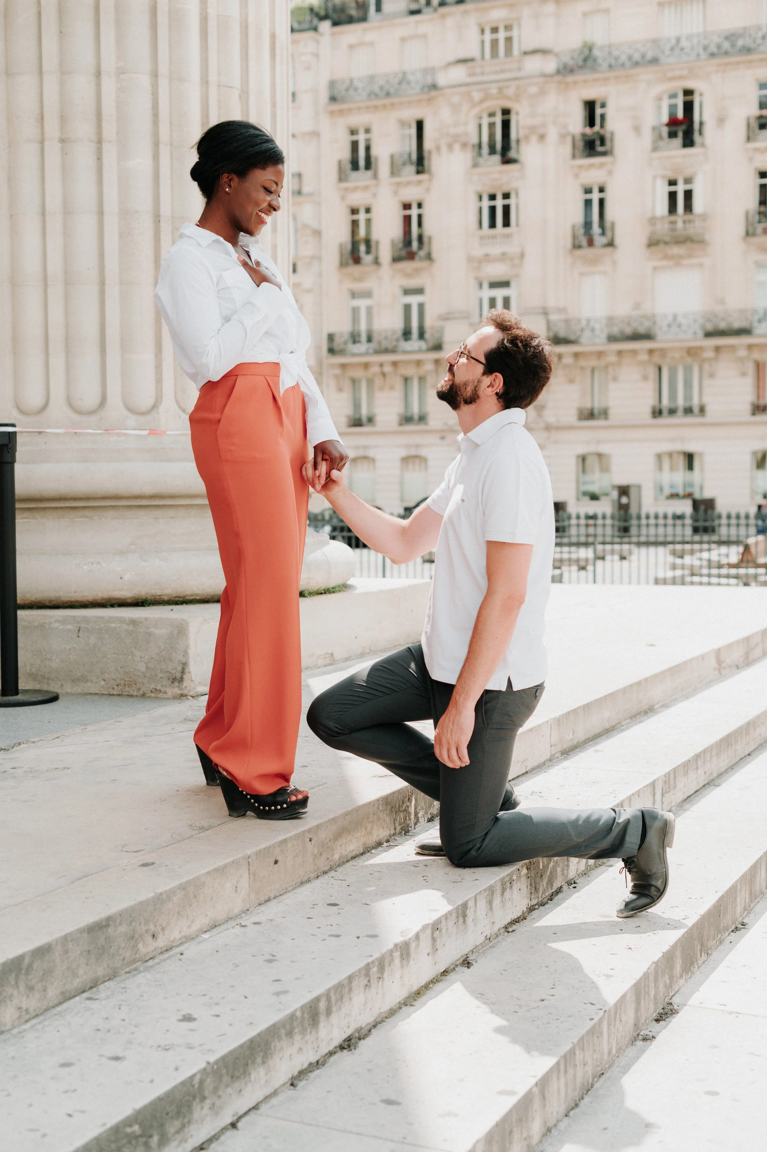 Un homme fait sa demande en mariage à une femme devant un bâtiment à Paris.