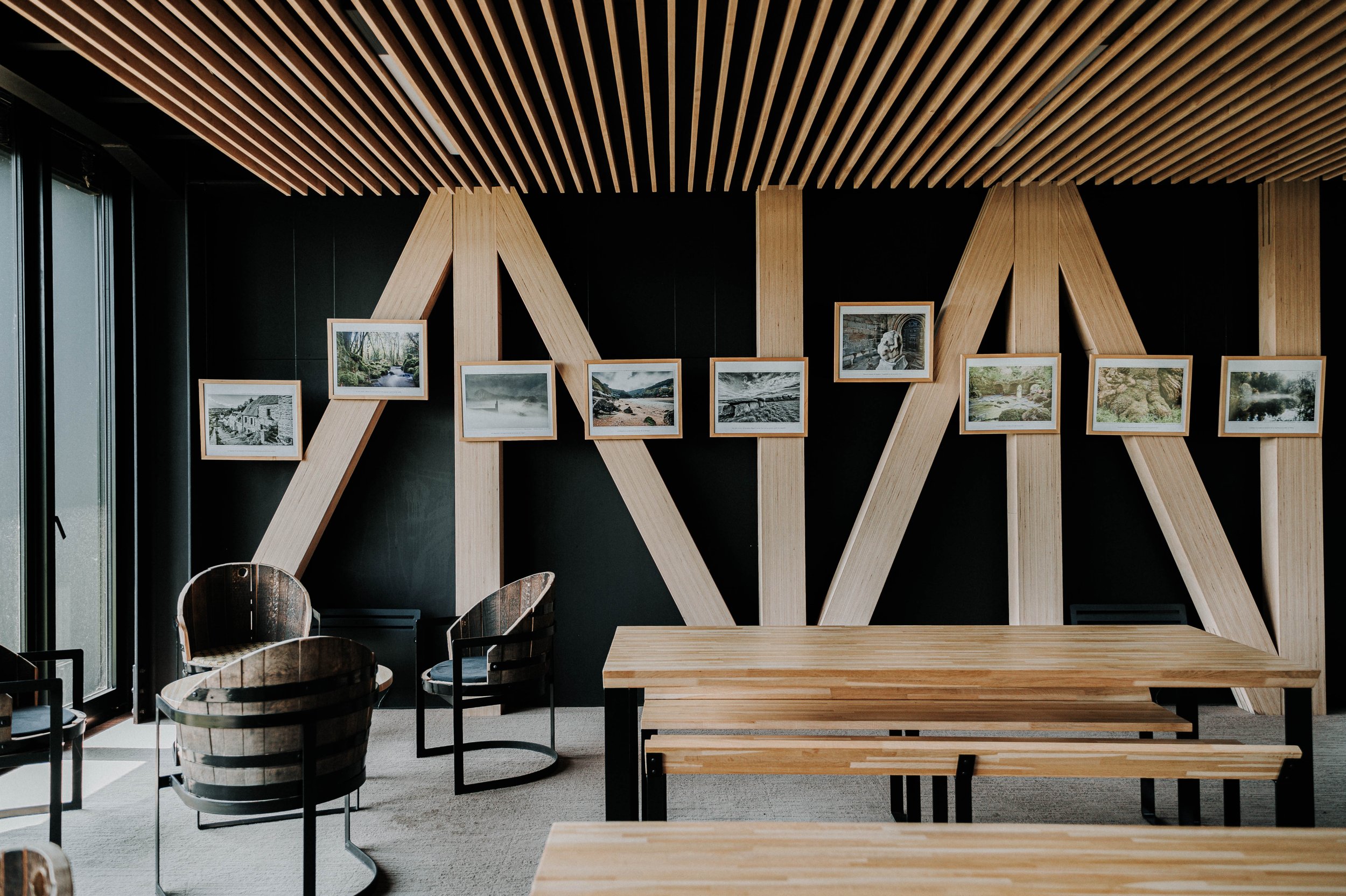 Intérieur moderne avec un mur en bois et des cadres photos, mobilier en bois avec tables et chaises en métal, lumière naturelle.