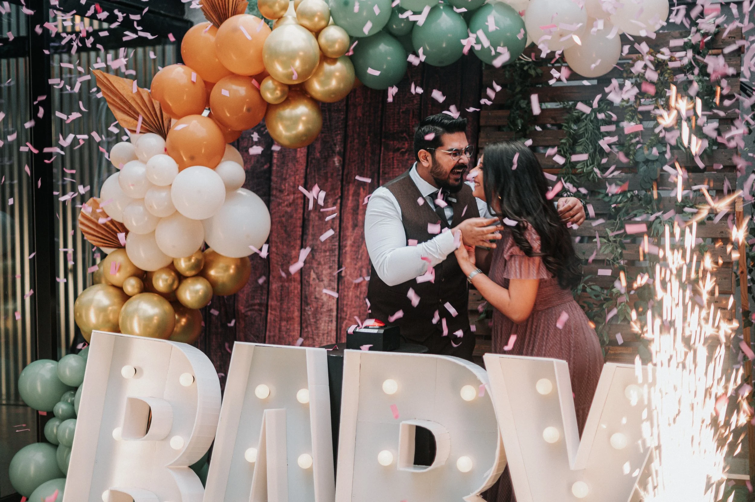 Un couple danse et célèbre leur mariage avec des ballons colorés et des feux d'artifice, entouré deconfettis roses