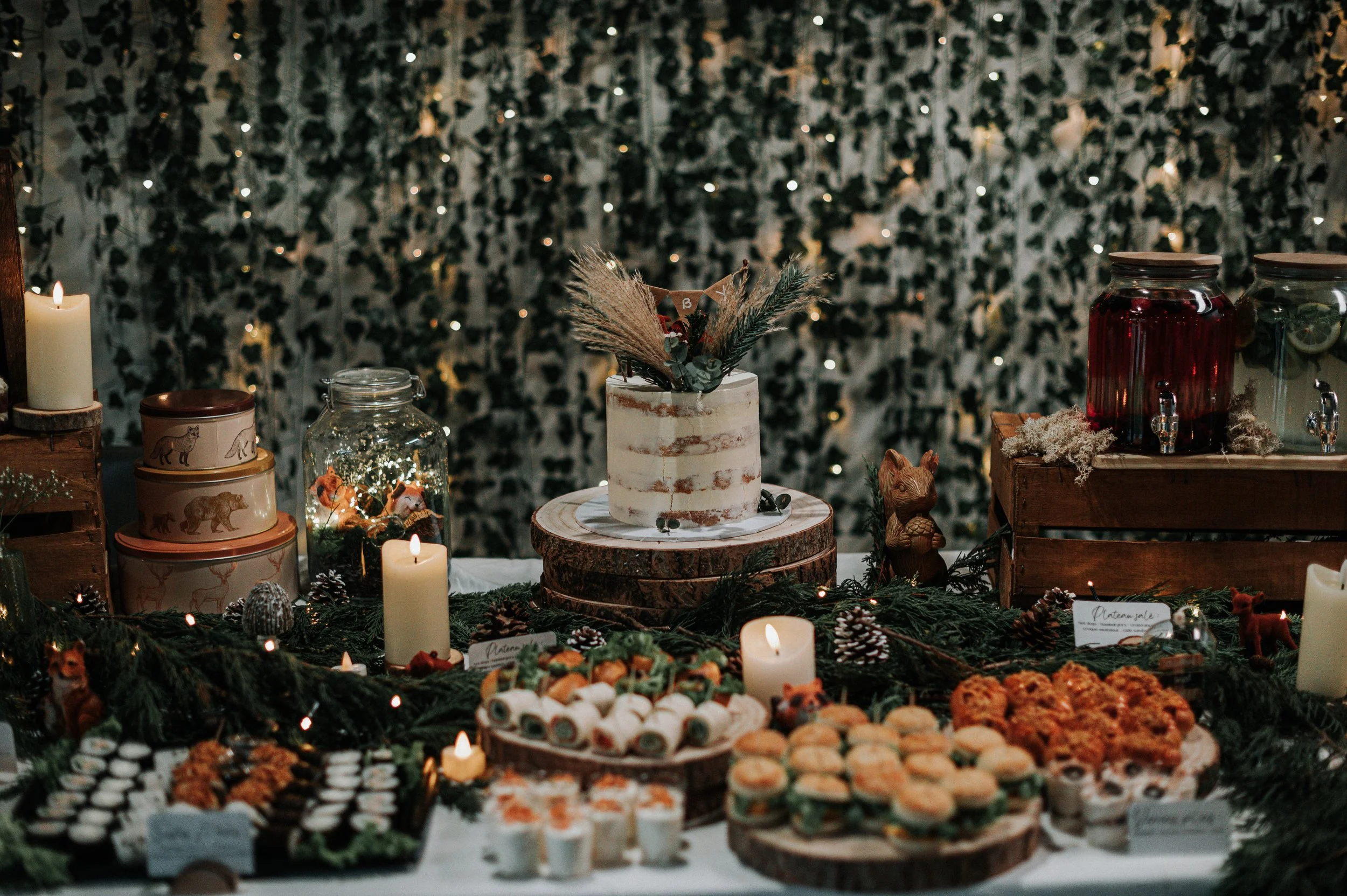 Table de fête décorée avec un gâteau au centre, entourée de tapas et de bougies, dans une ambiance chaleureuse et festive.