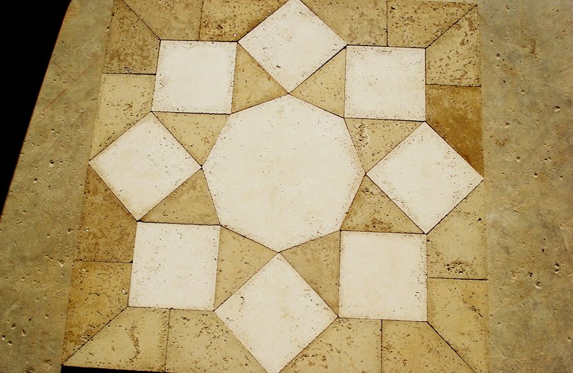 Pattern of white tiles arranged in a decorative design on a beige tiled floor.
