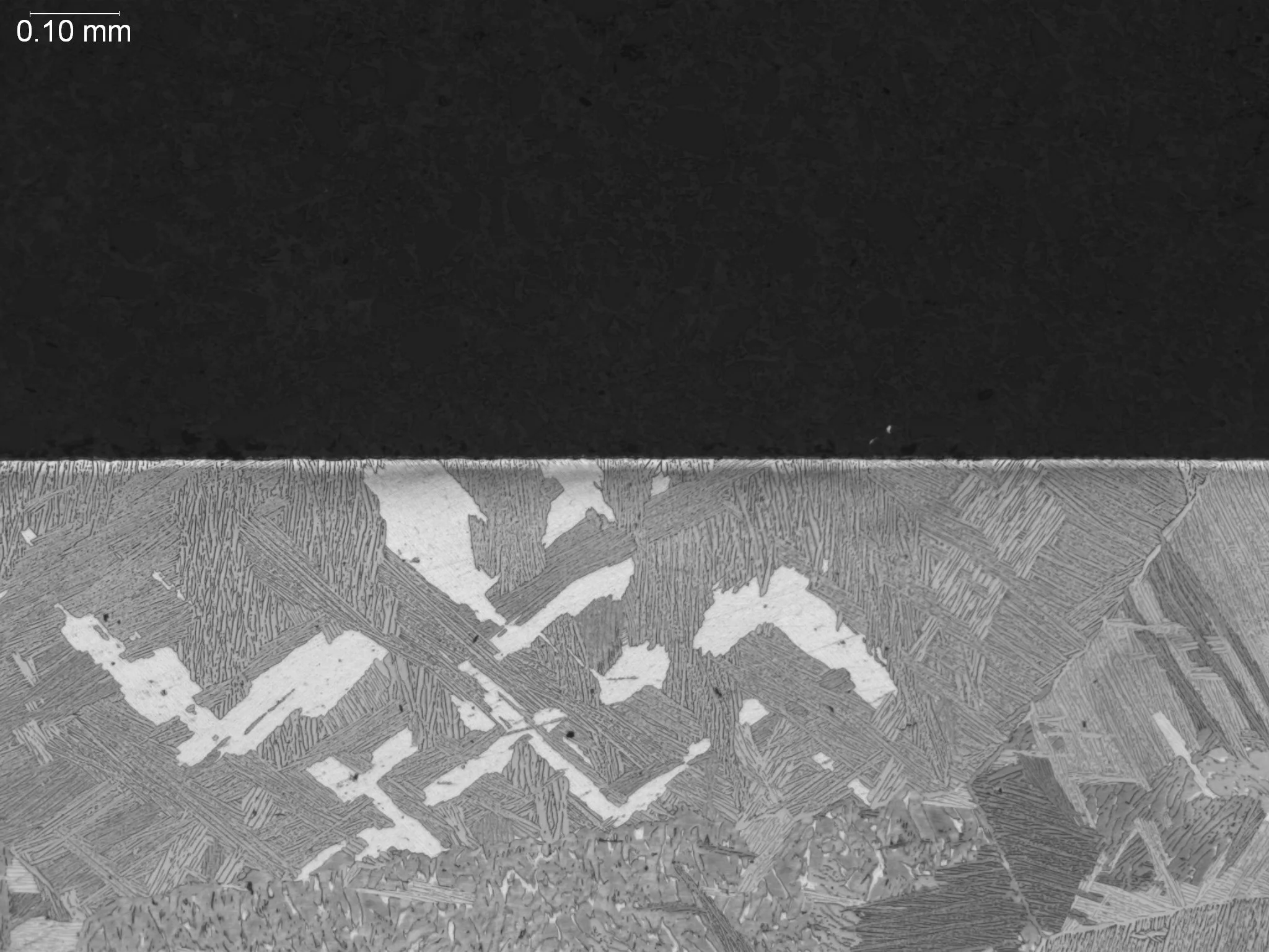 Alpha case on cast titanium at 100x magnification, metallographic cross-sectional evaluation identifying a brittle alpha-stabilized surface layer, oxygen-rich phase contamination depth, and underlying transformed beta matrix morphology per GE S-400 q