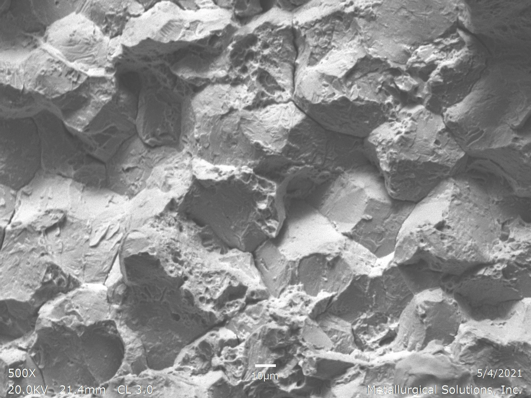 Fracture 500x, scanning electron microscope SEM fractography evaluation identifying an intergranular fracture mode showing rocky, facet-like grain boundary separation per ASTM E3 under ISO 17025 accredited laboratory standards.
