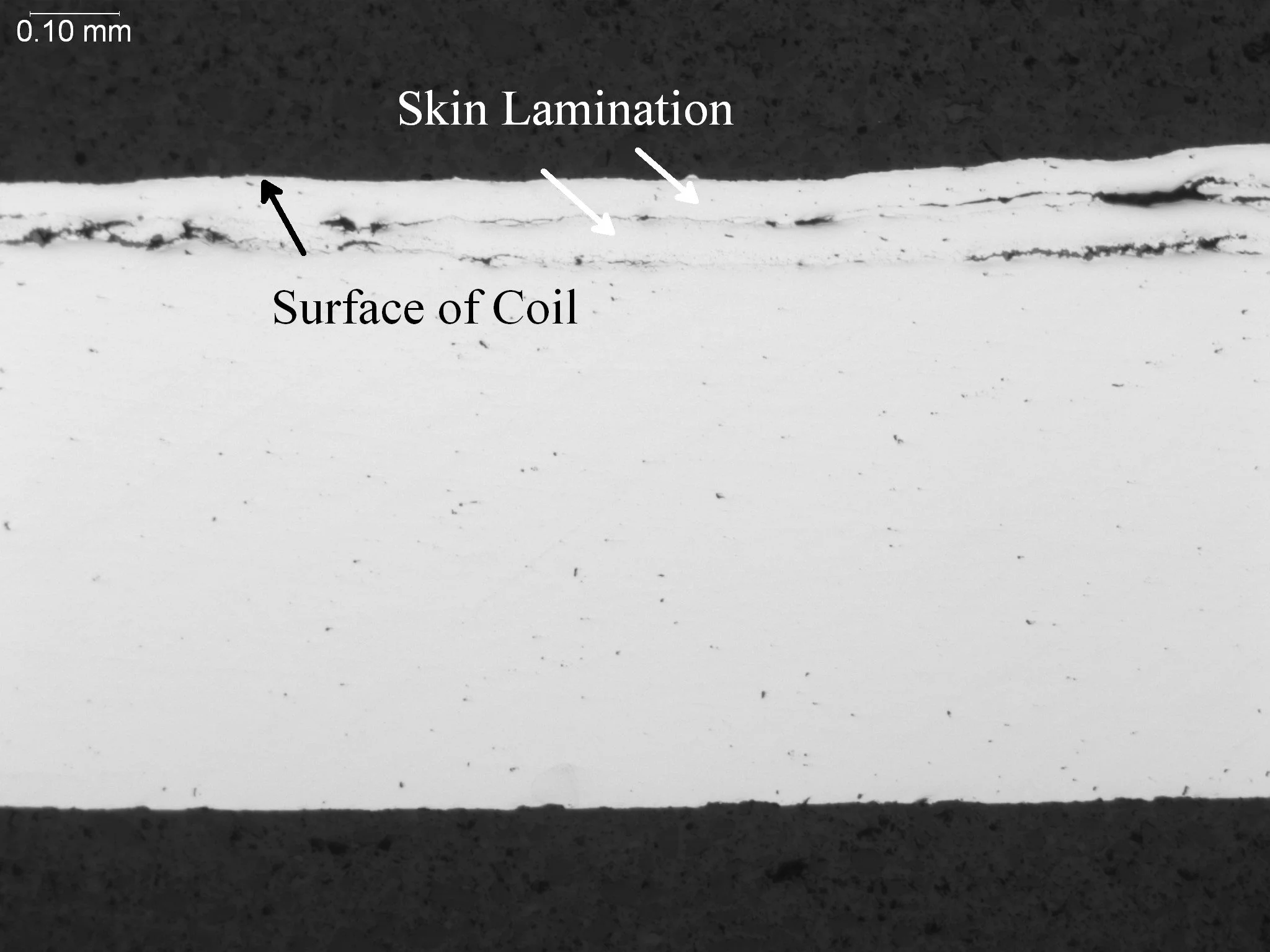 Surface skin lamination defect within a rolled steel coil sheet profile, metallographic cross-sectional evaluation identifying continuous sub-surface mechanical separations, elongated oxide inclusion stringers, and structural layer delamination per A