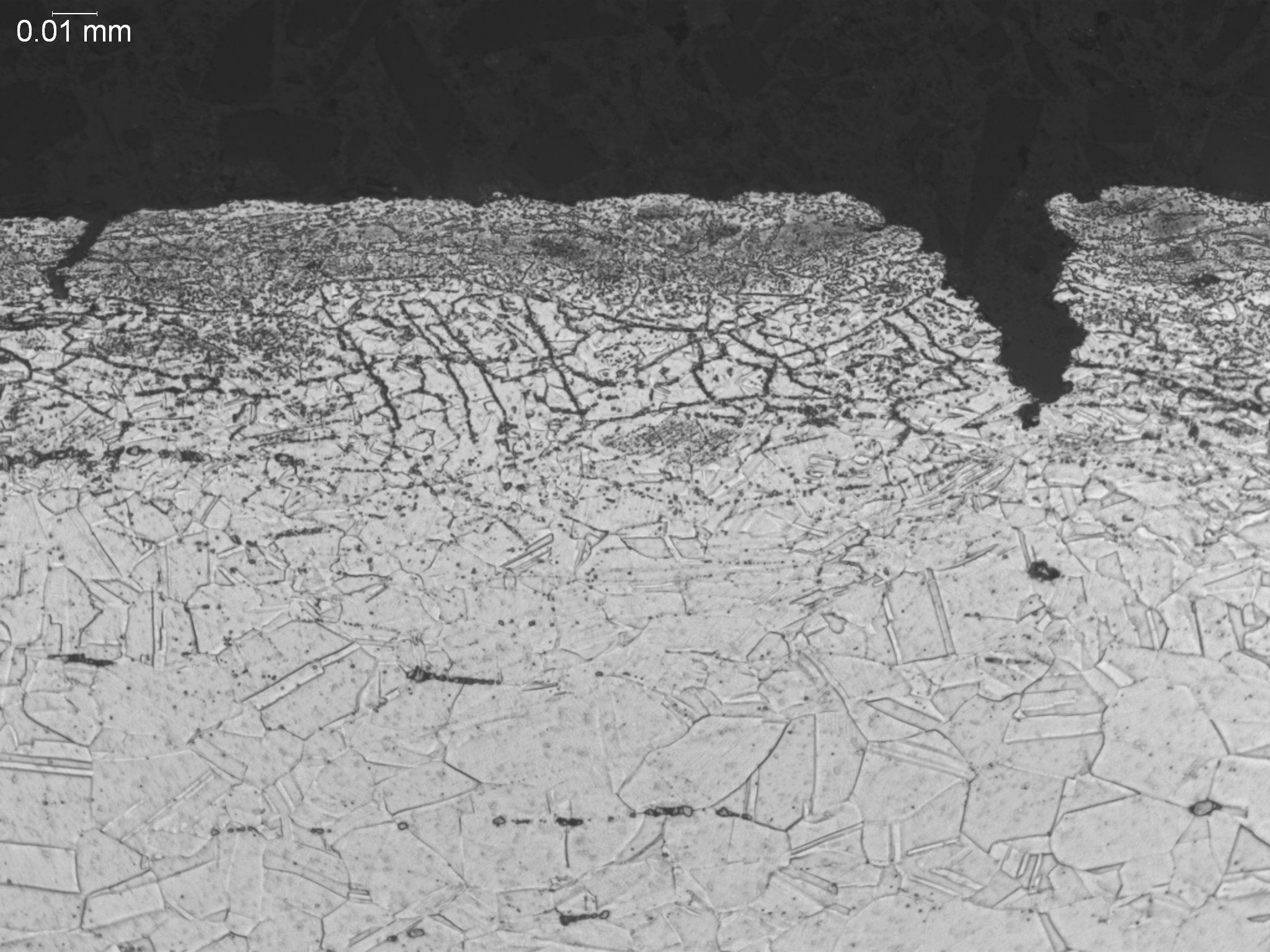 Carburization within a nickel-base superalloy matrix, metallographic cross-sectional evaluation revealing dense subsurface grain boundary carbide networks and localized environmental pitting within the altered microstructure per ASTM E3 under ISO 170