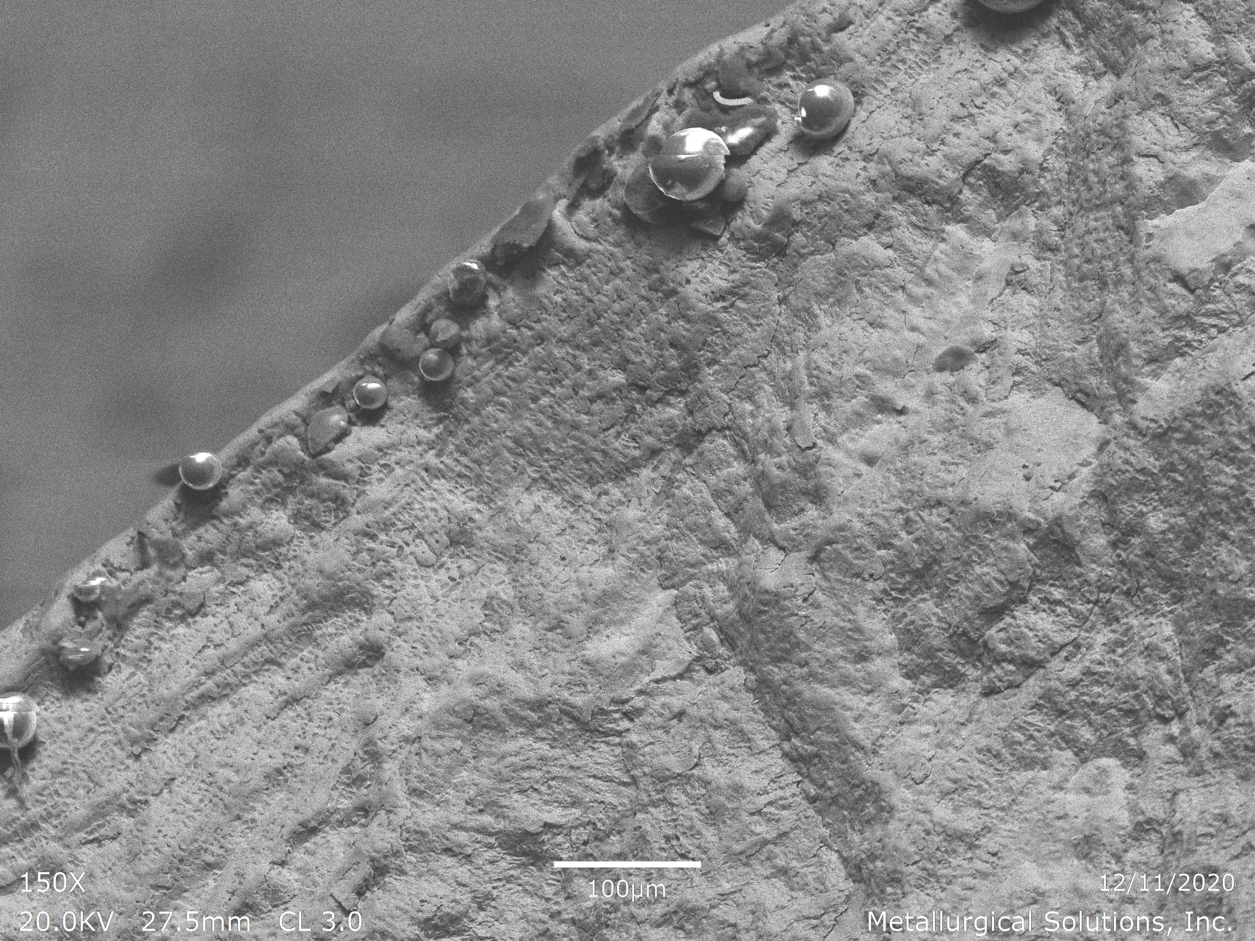 Fracture initiation site showing mechanical deformation and micro-void morphology, scanning electron microscope SEM fractography evaluation identifying localized stress concentration and cracking initiation along a component edge profile per ASTM E3 