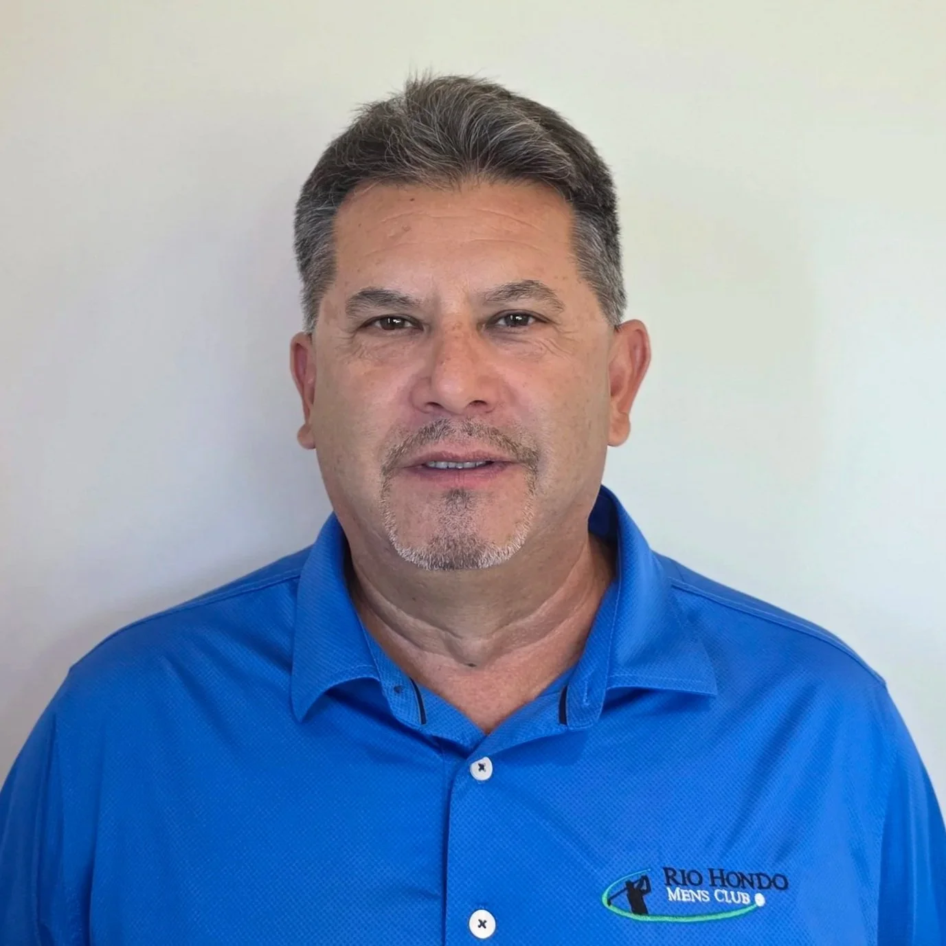 A man wearing a black Rio Hondo Men's Club polo shirt, smiling against a plain background.