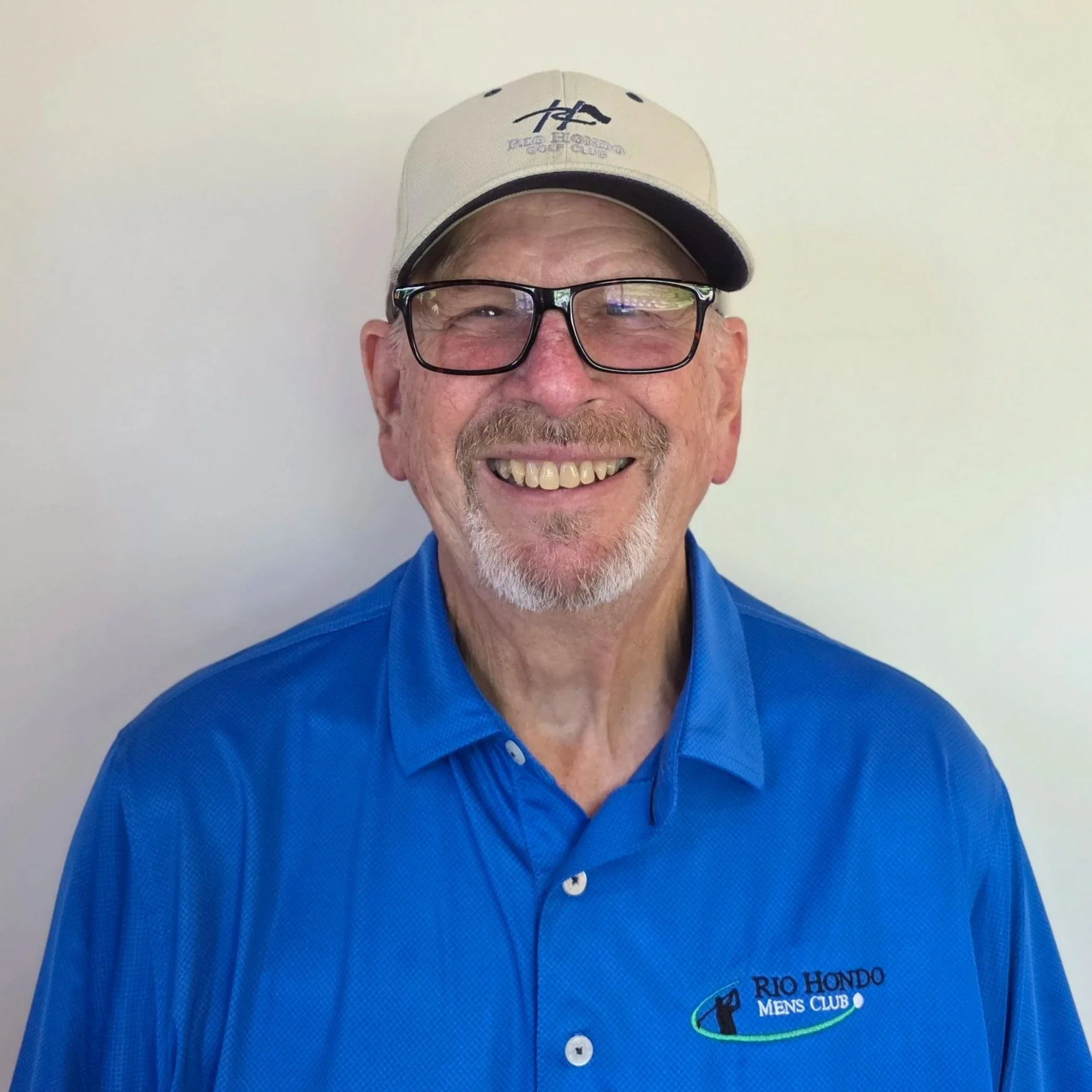 Man wearing a Rio Hondo Men's Club cap and shirt, smiling at the camera.