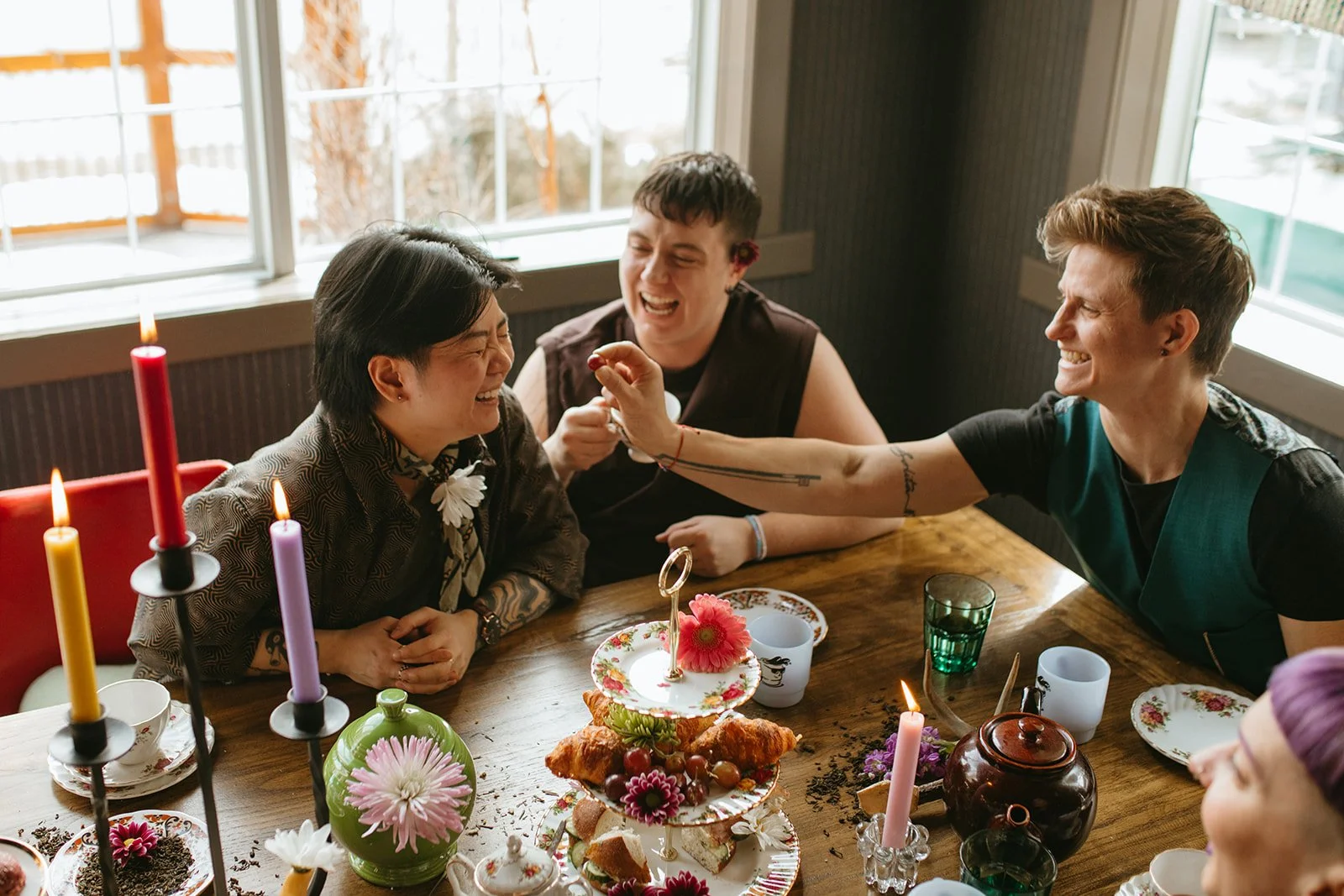 A group of friends celebrating with a cake, candles, and decorations, laughing and enjoying each other's company.