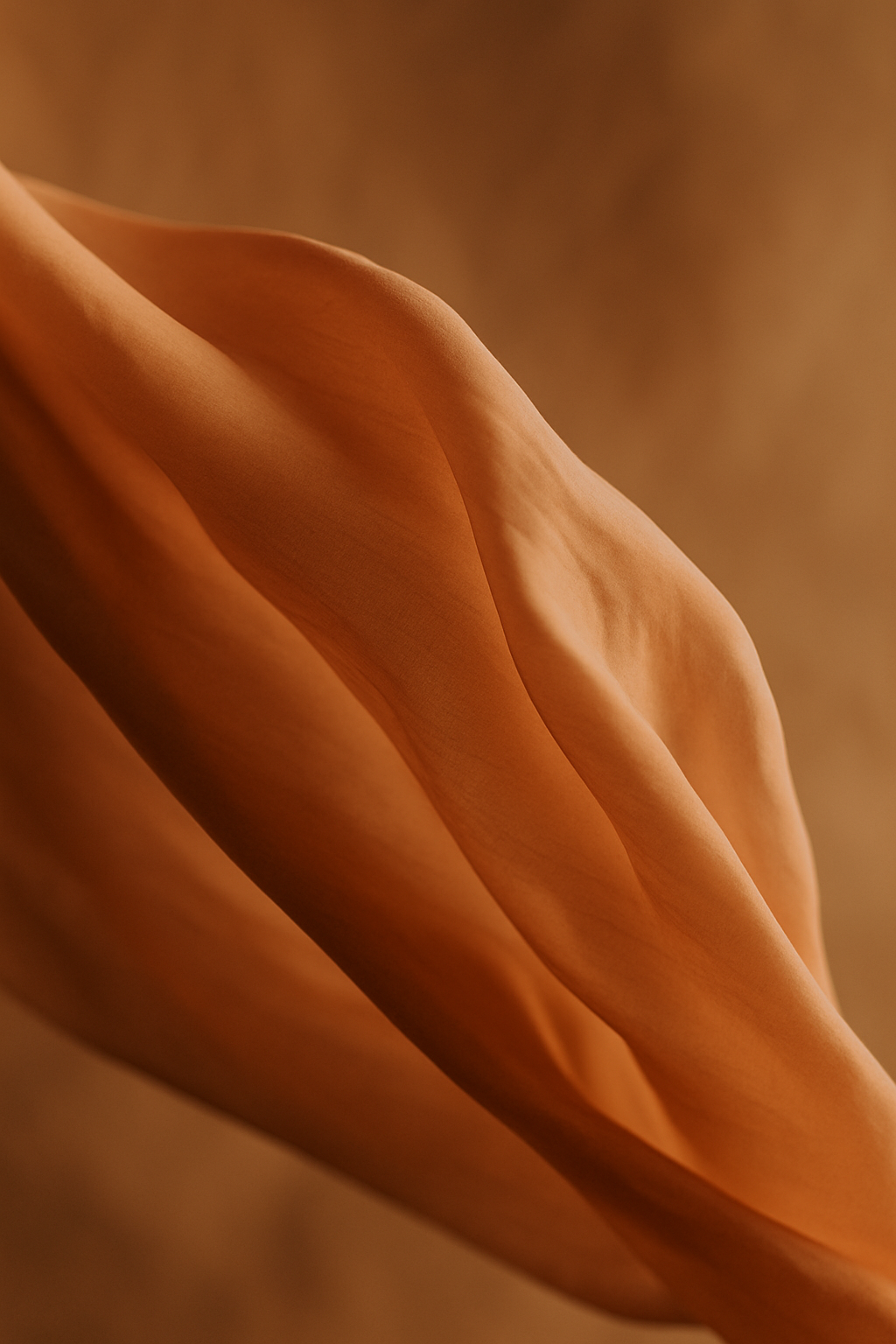Close-up of a soft, flowing fabric in warm, earthy tones.