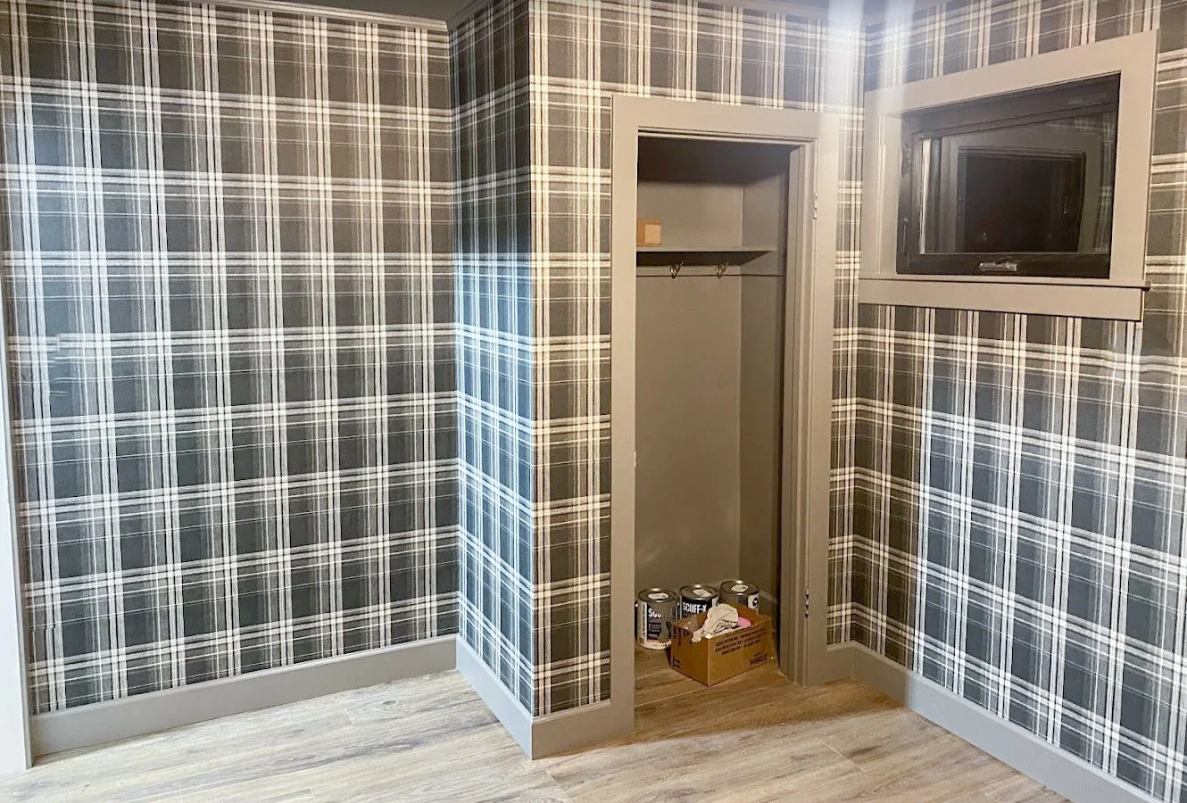 Room with plaid wallpaper, an open closet with shelves, and a small window.