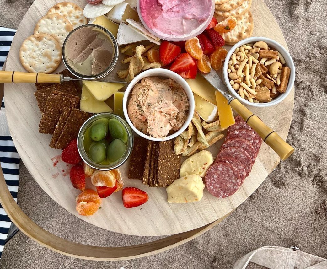 Charcuterie board with crackers, cheese, sliced meats, fruits, nuts, spreads, and dipping sauces.