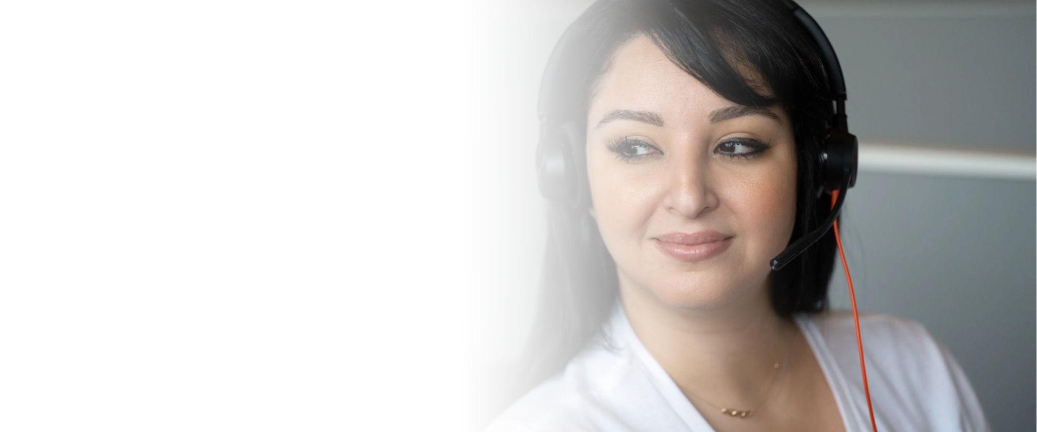 Close-up of a woman with dark hair wearing a headset, looking to the side with a slight smile.